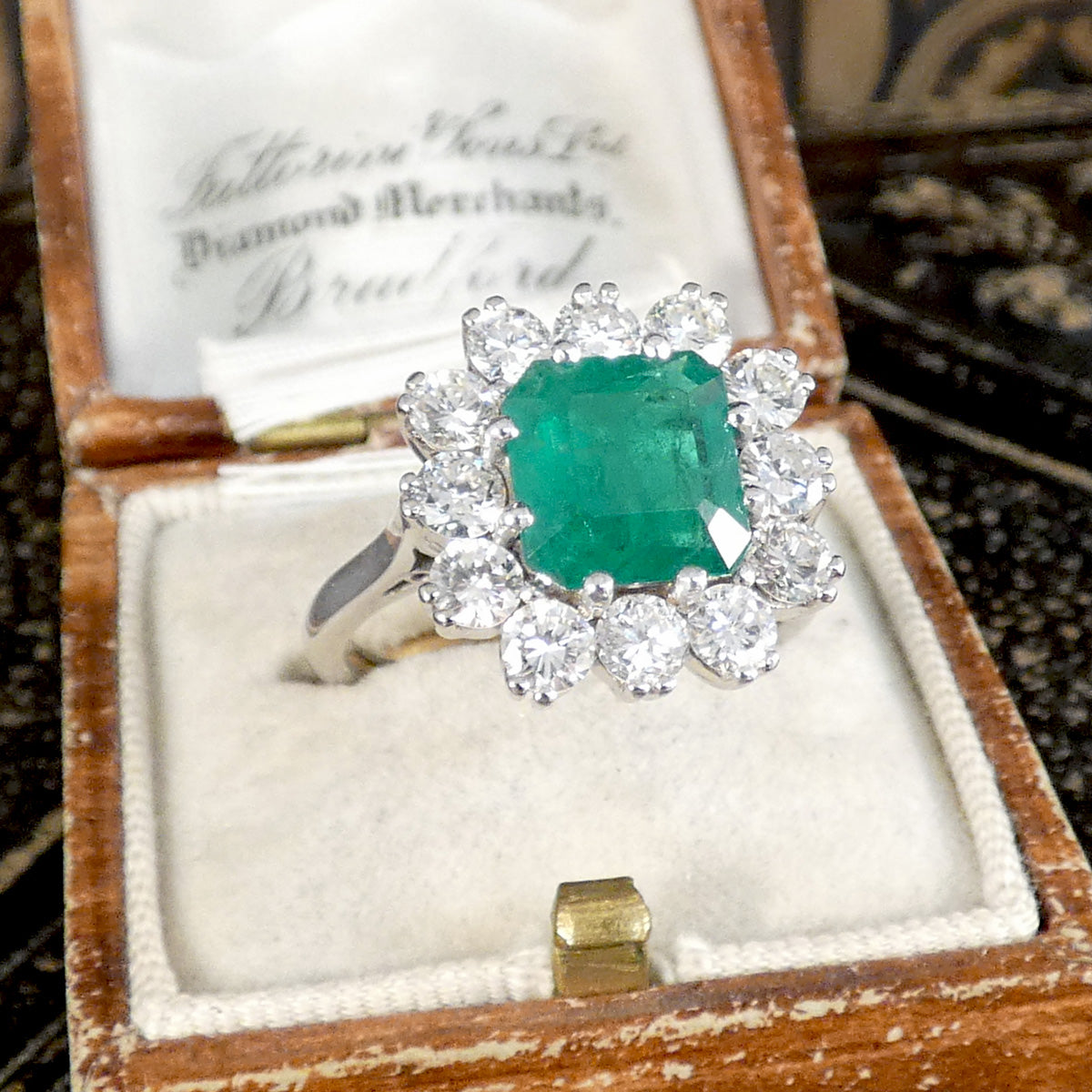 A big and beautiful statement ring set with a centre squared emerald cut Emerald in an 8 claw setting surrounded by 12 round brilliant cut diamonds creating an amazing sparkle. Displayed in a vintage box.