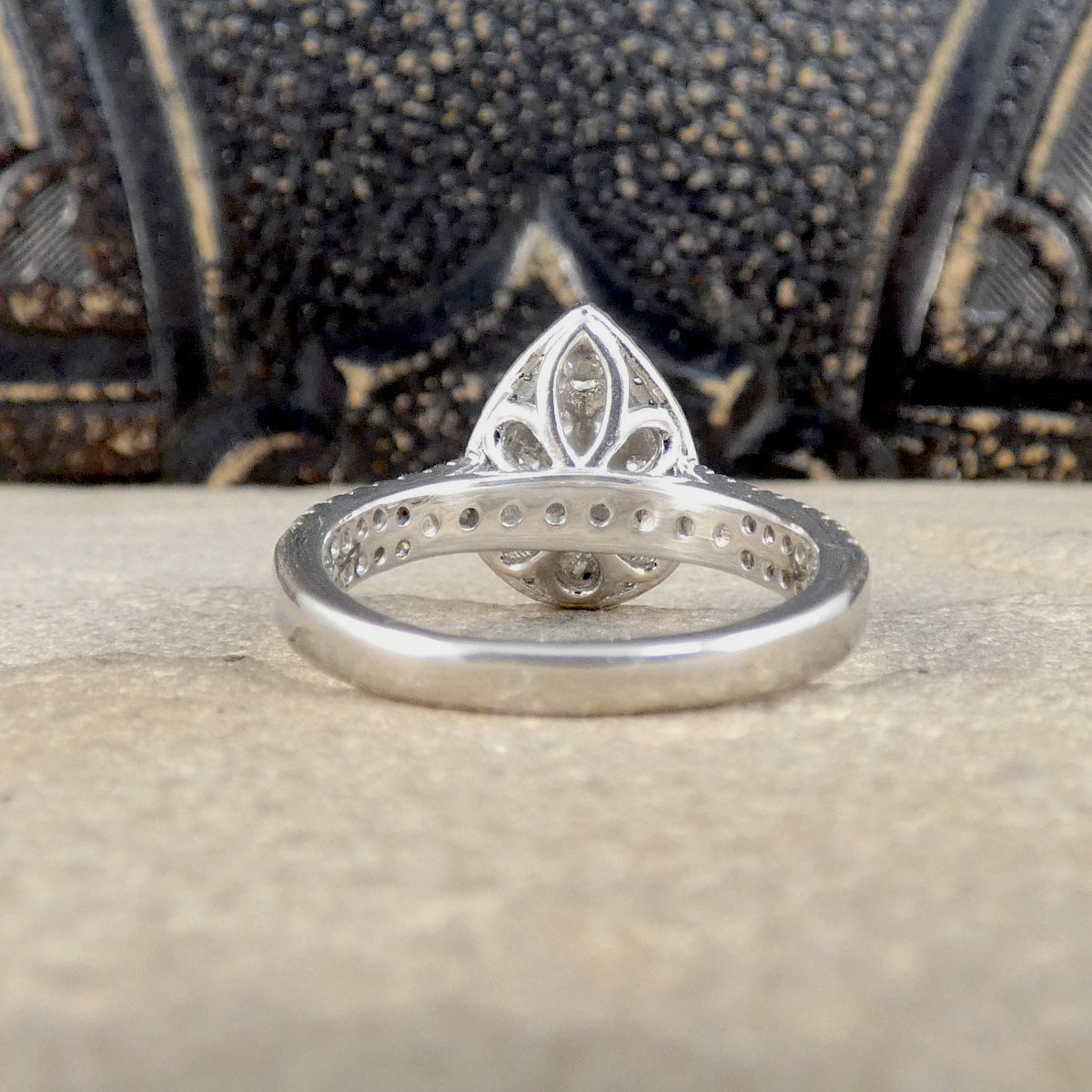 Silver ring with intricate design on a textured surface