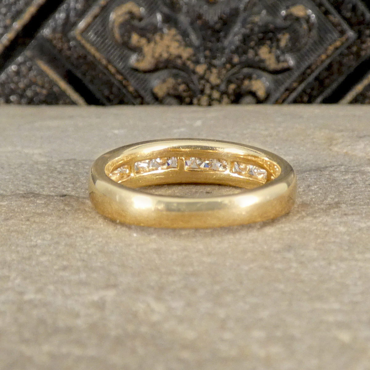 Gold ring with embedded diamonds on a textured surface