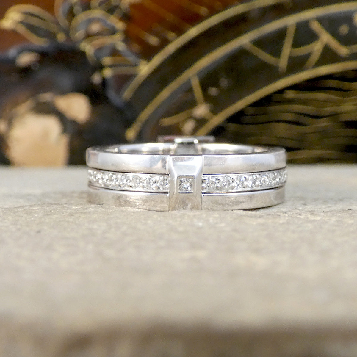 Platinum ring with diamond accents on a textured surface