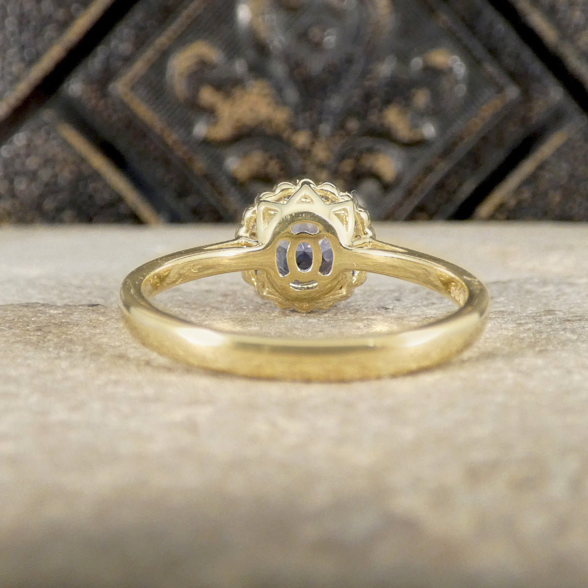 Gold ring with intricate design on a textured surface