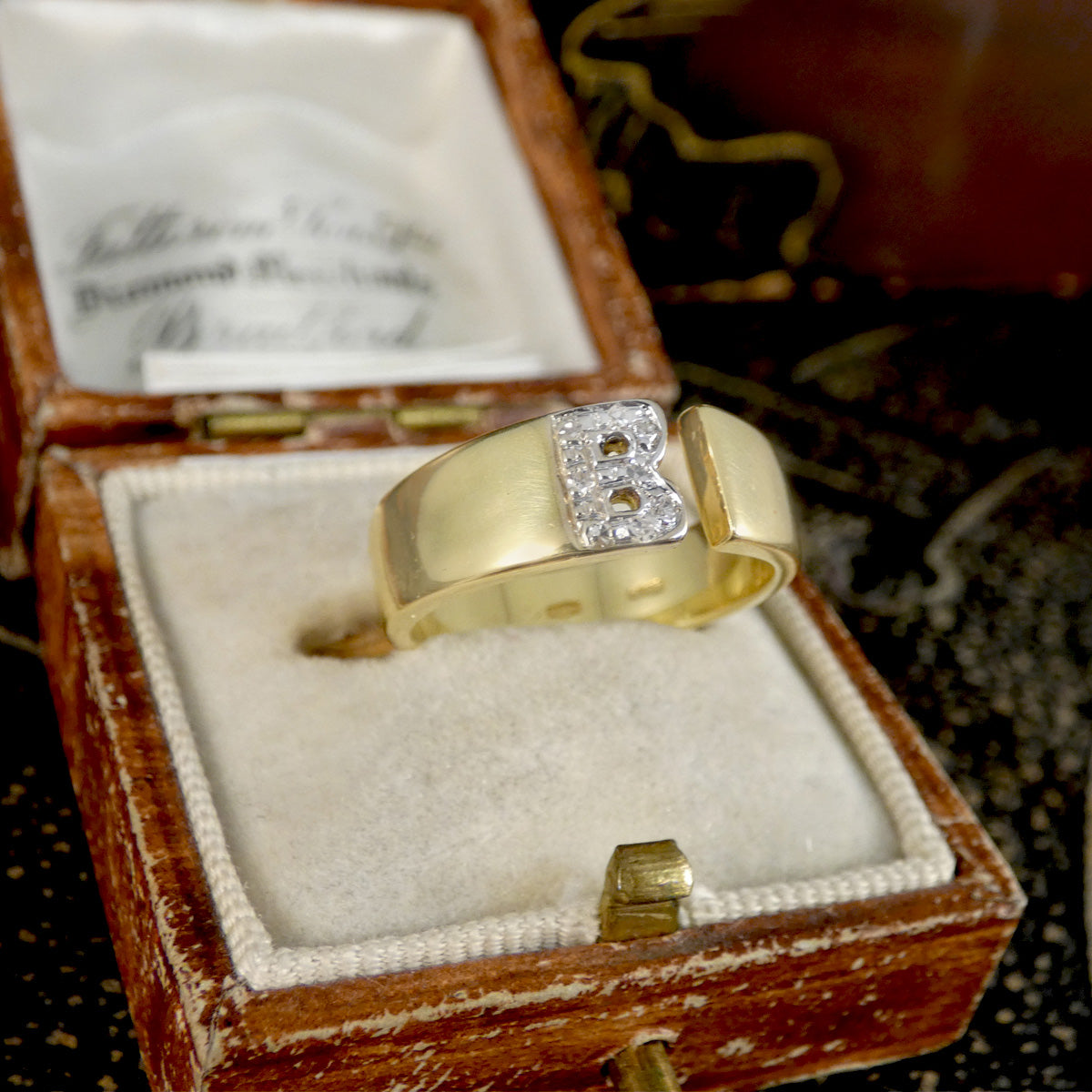 Gold ring with a diamond set B initial in a wooden box
