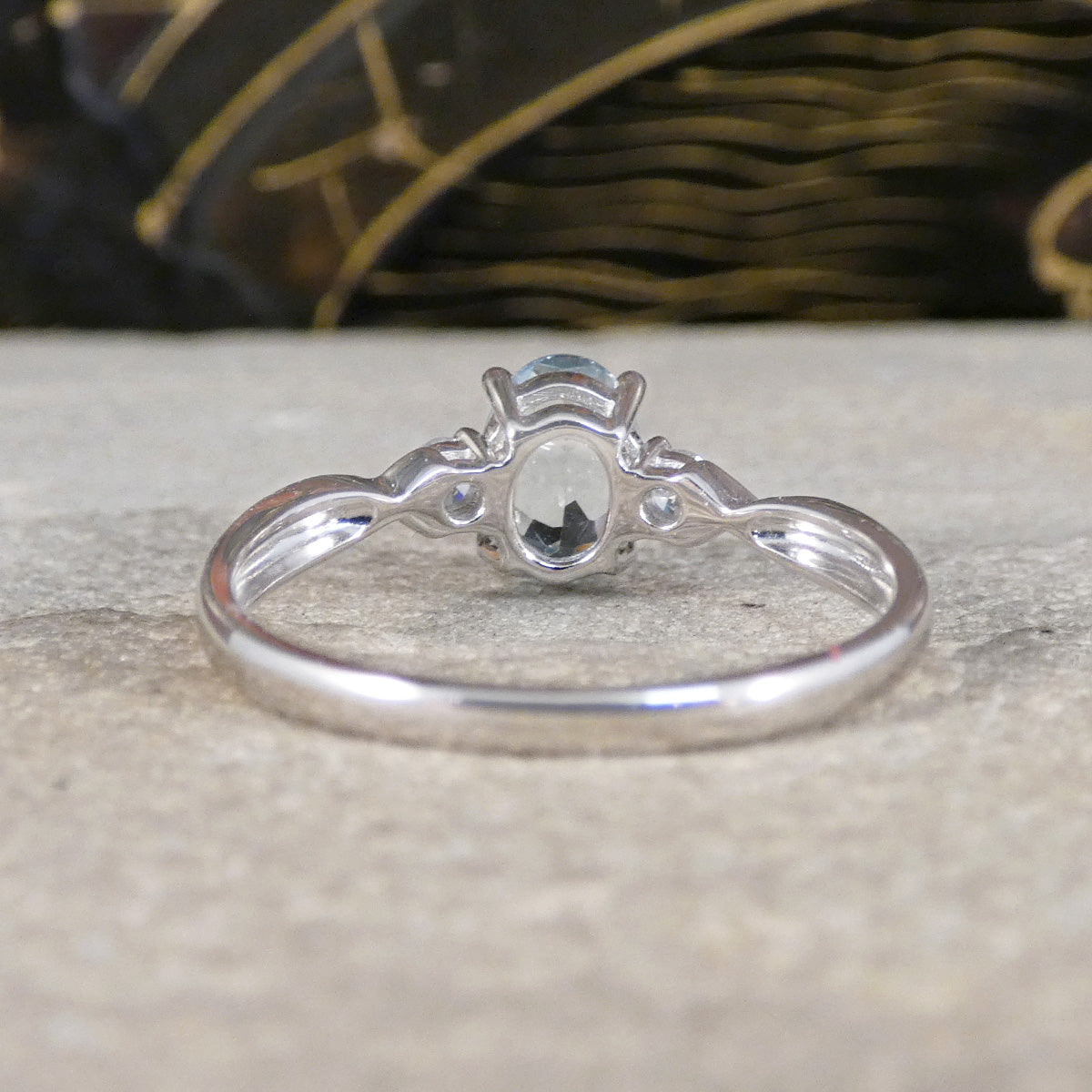 Back view of Modern Oval Cut Aquamarine and Brilliant Cut Diamond Three Stone in Platinum. Showing open setting allowing light to pass through.
