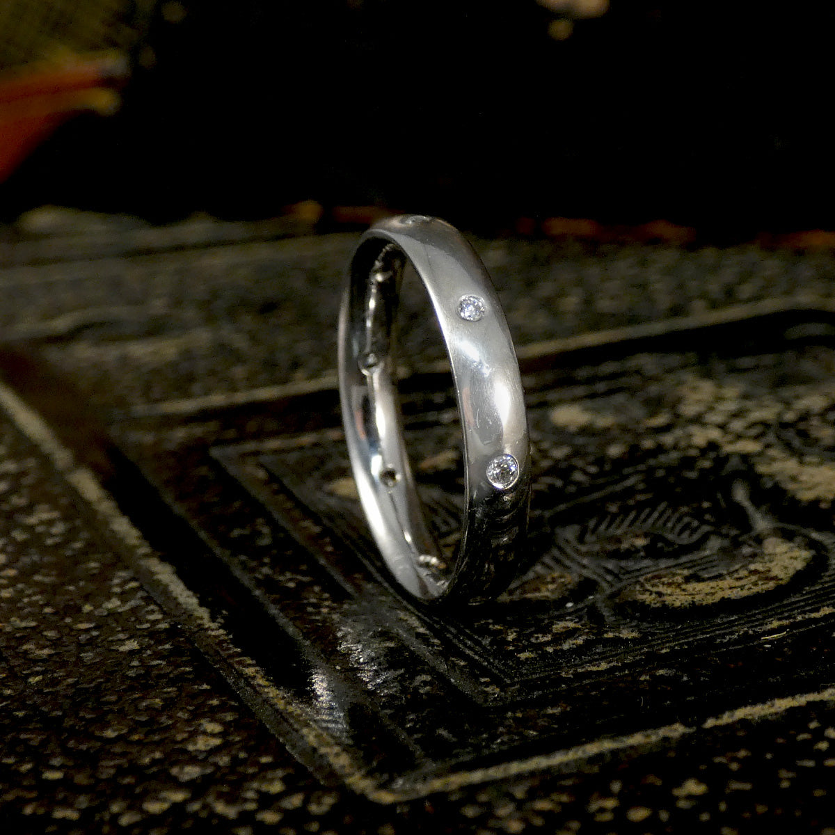 Silver ring with embedded diamonds on a textured surface
