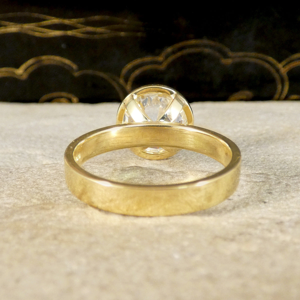 A diamond solitaire ring in a rub over bezel setting in 18ct yellow gold