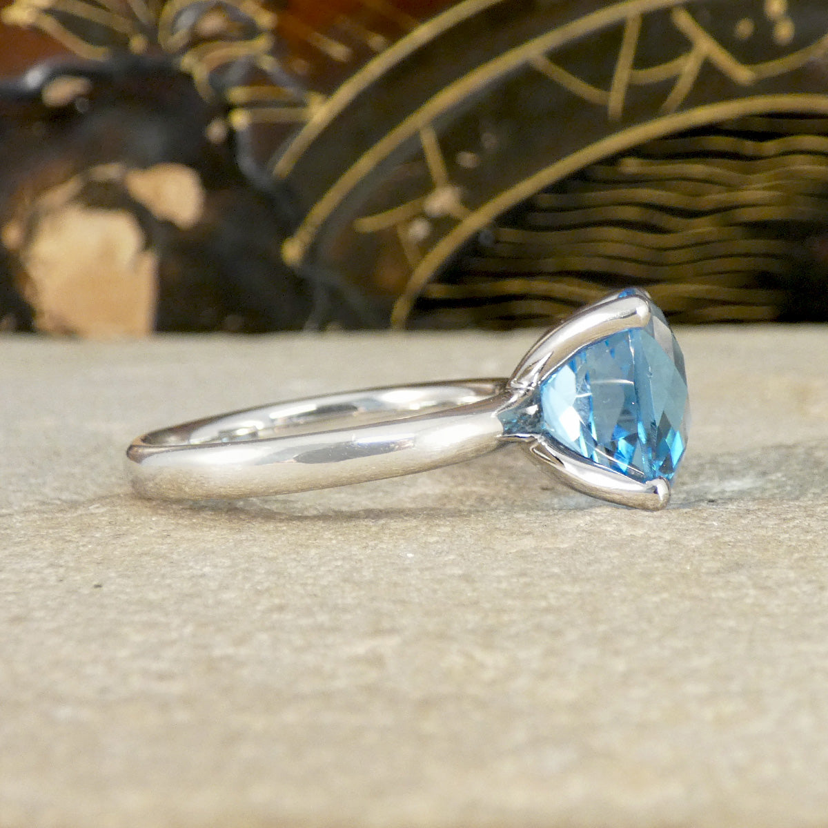 white gold ring with a blue topaz gemstone on a textured surface