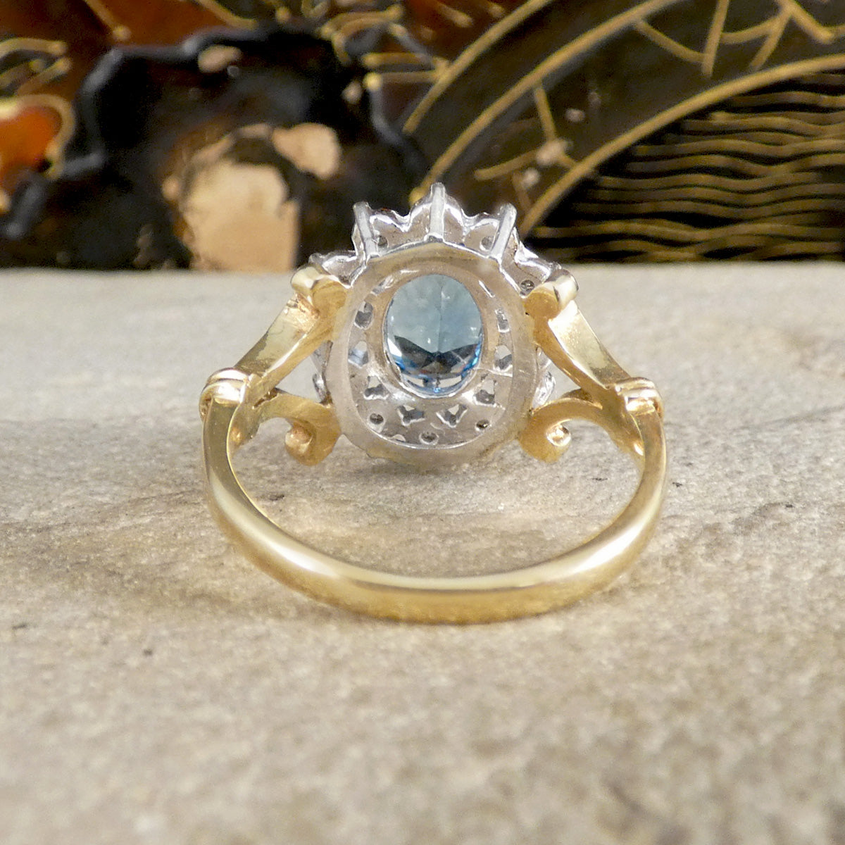 Gold and silver ring with a blue gemstone on a textured surface