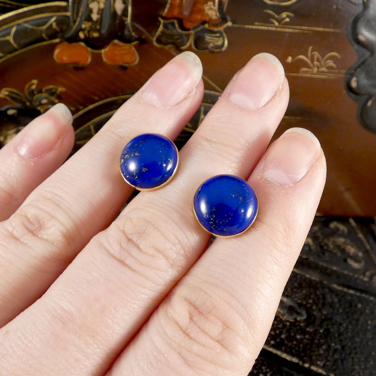 Large blue Lapis Lazuli stud earrings in 9ct yellow gold shown on a hand for size referrence.