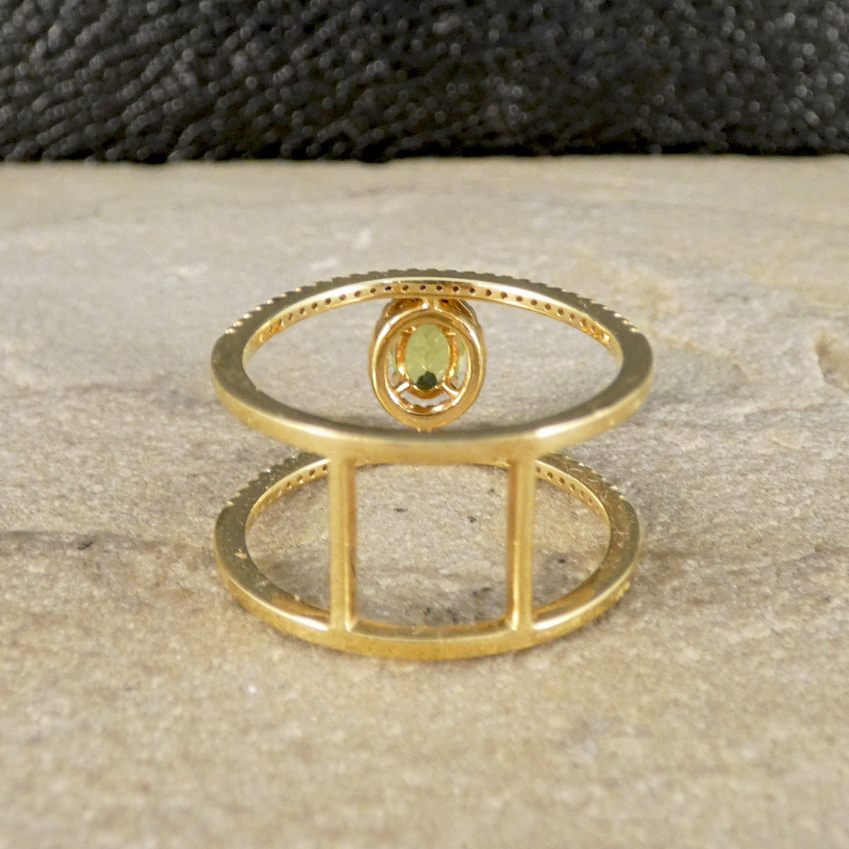 Gold ring with a green gemstone on a textured surface