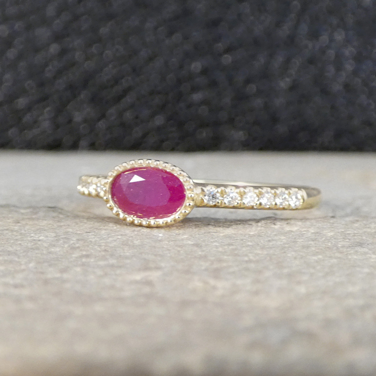 Gold ring with a pink gemstone on a textured surface