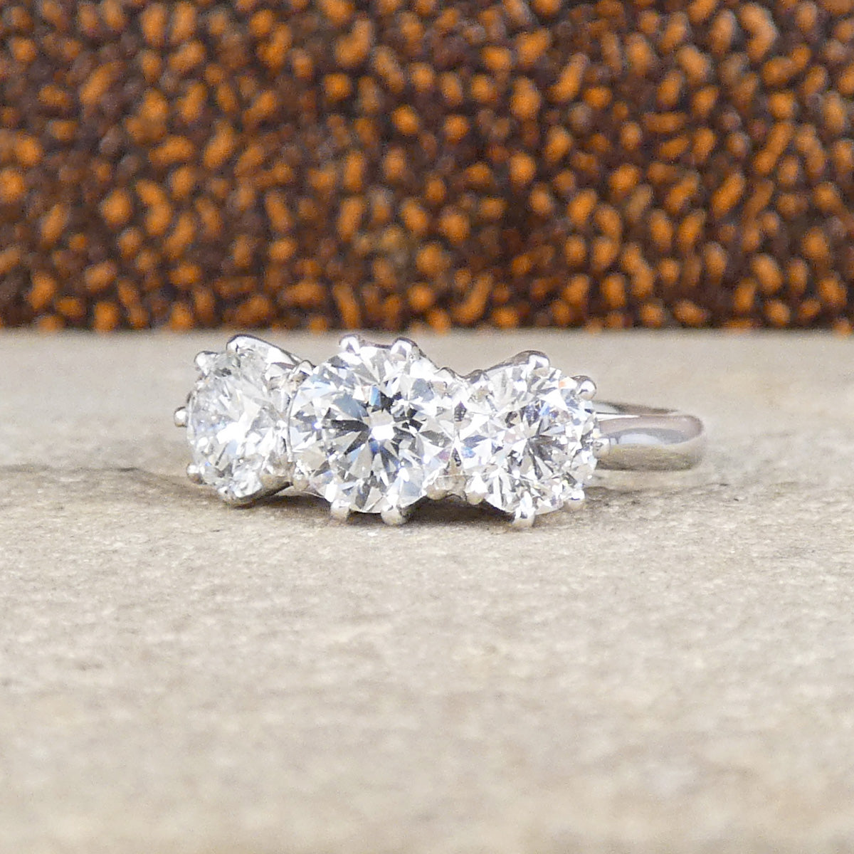 Diamond ring with three stones on a textured surface