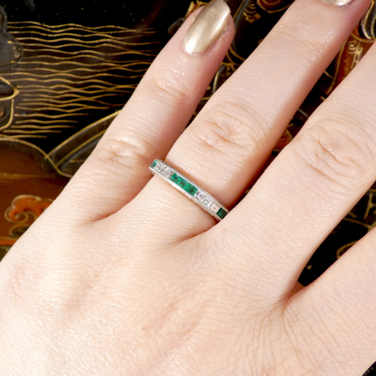 Art Deco Inspired Emerald and Diamond Full Eternity Ring in Platinum shown on the finger.