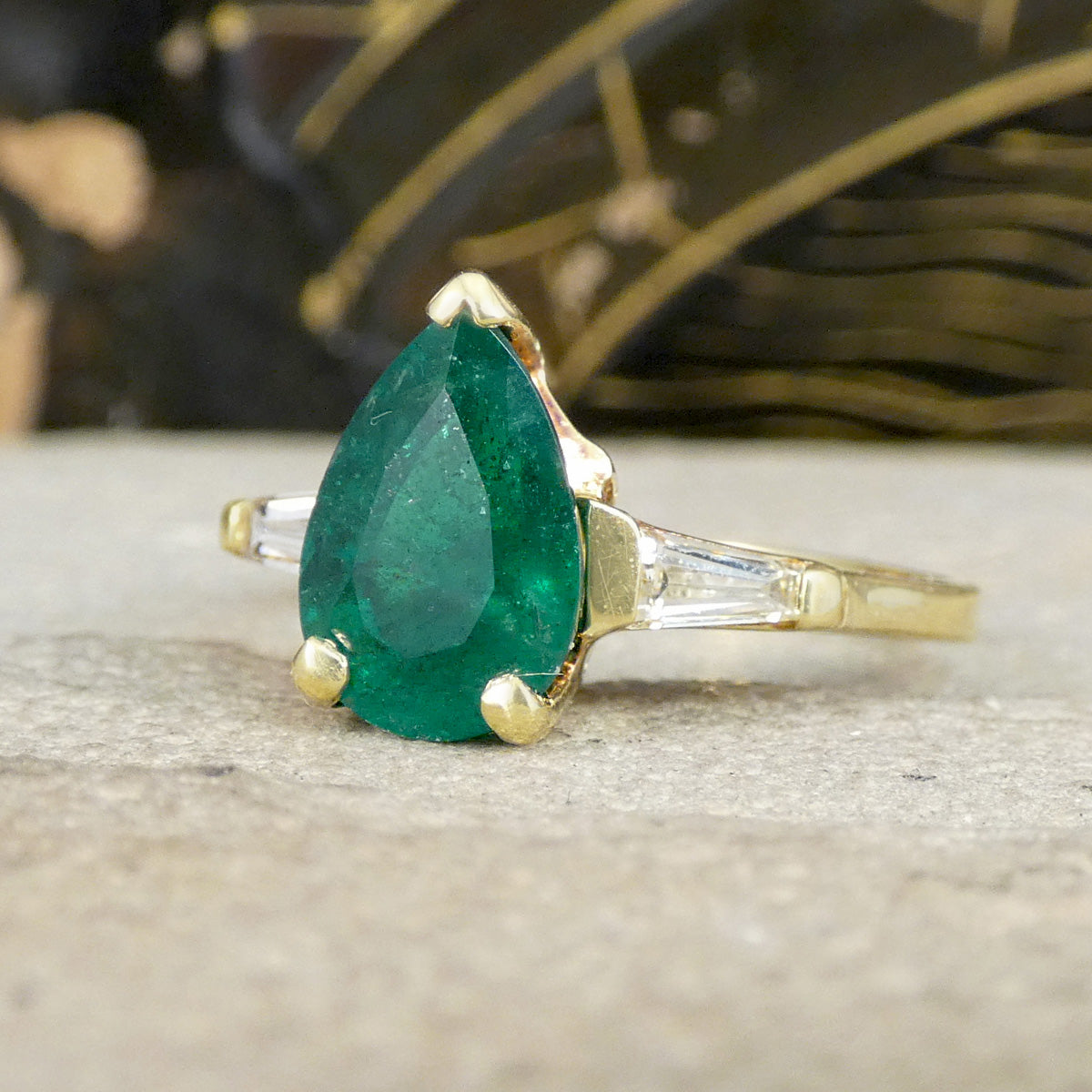 Gold ring with a green gemstone on a textured surface