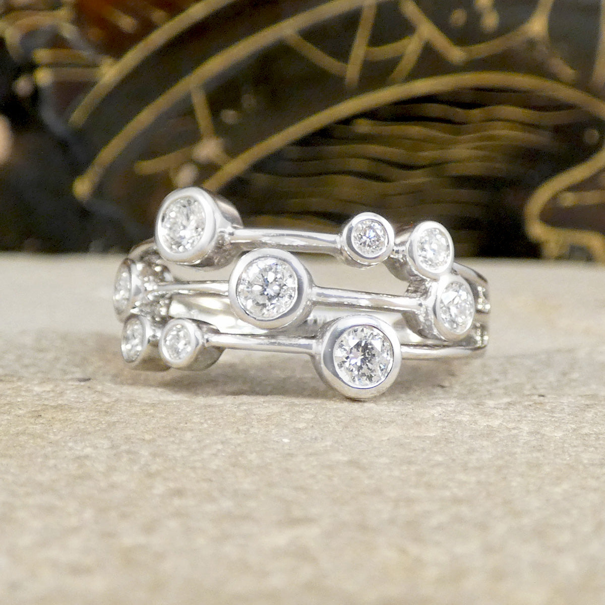 Stack of silver rings with diamond-like stones on a textured surface