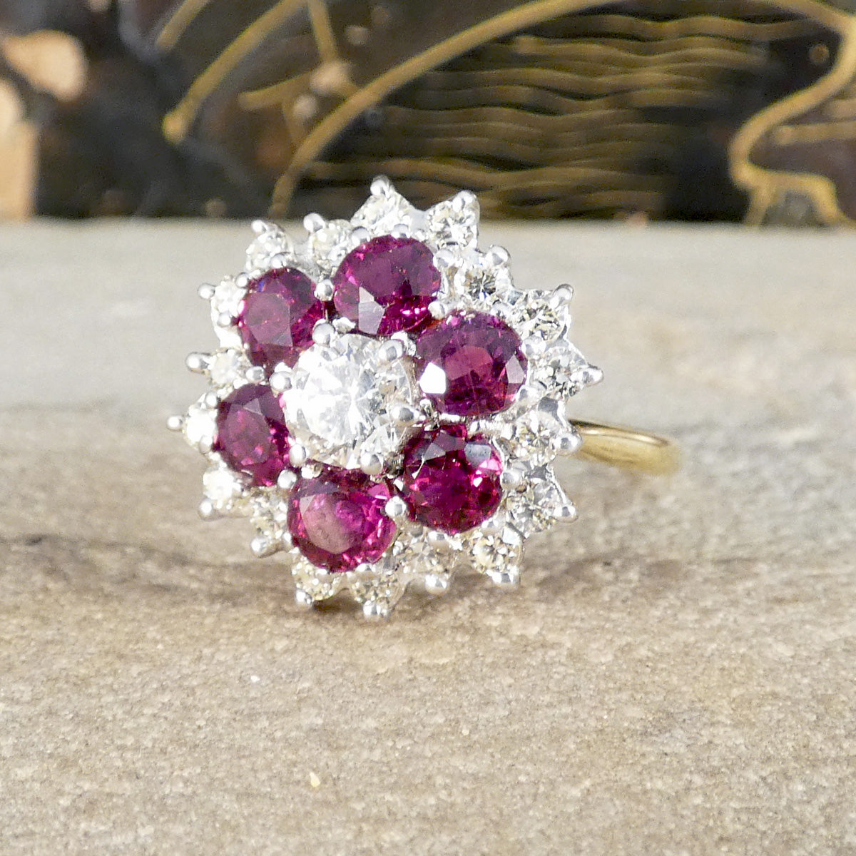 Ring with red gemstones and diamonds on a textured surface