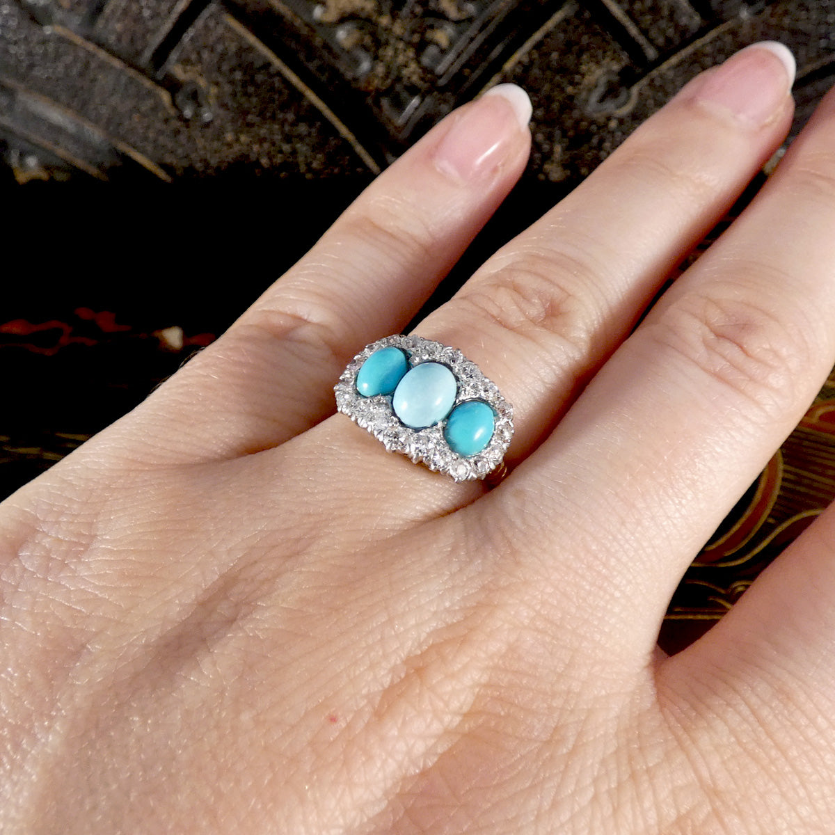 Antique Turquoise ring on a hand with a dark textured background
