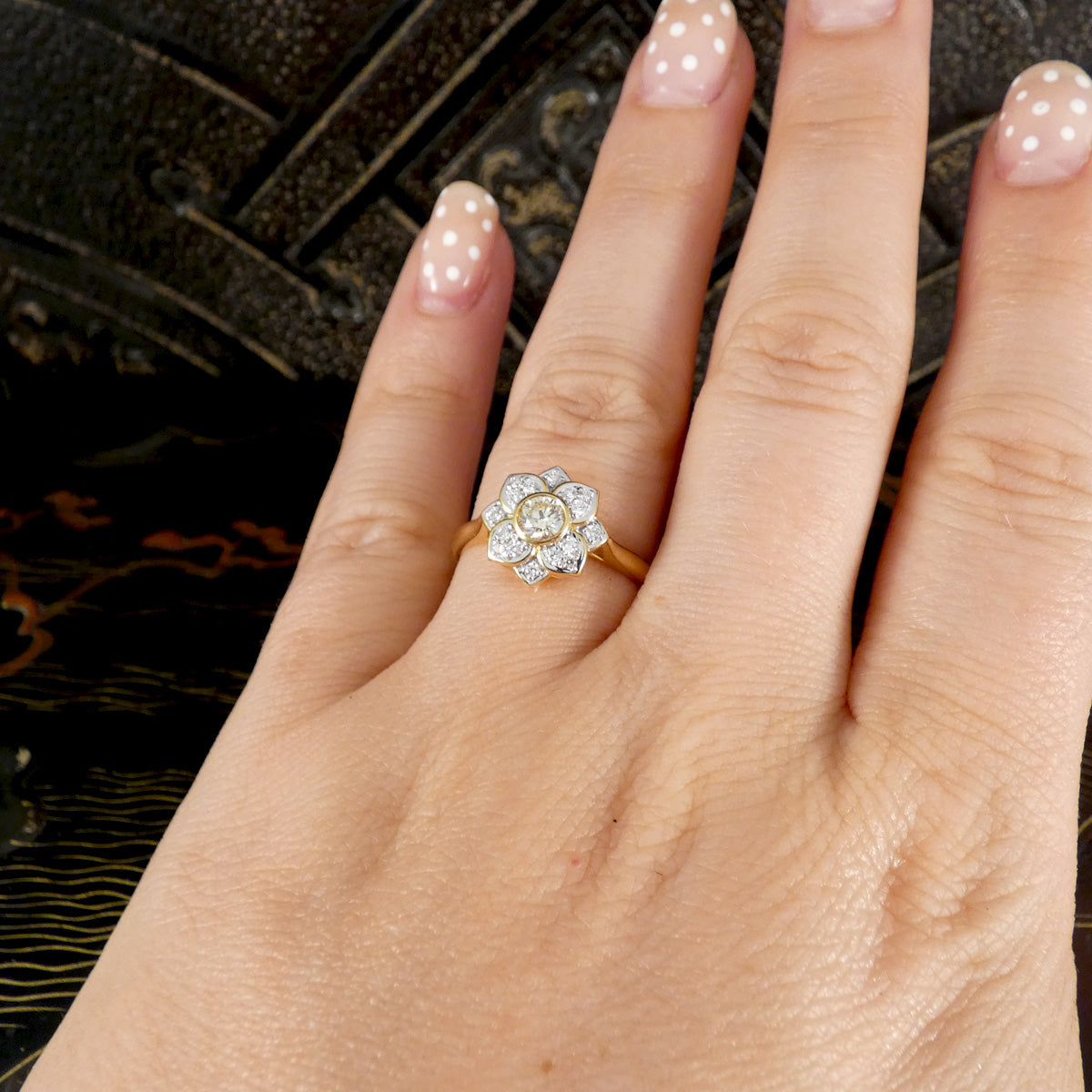 Hand wearing a diamond ring with a dark background