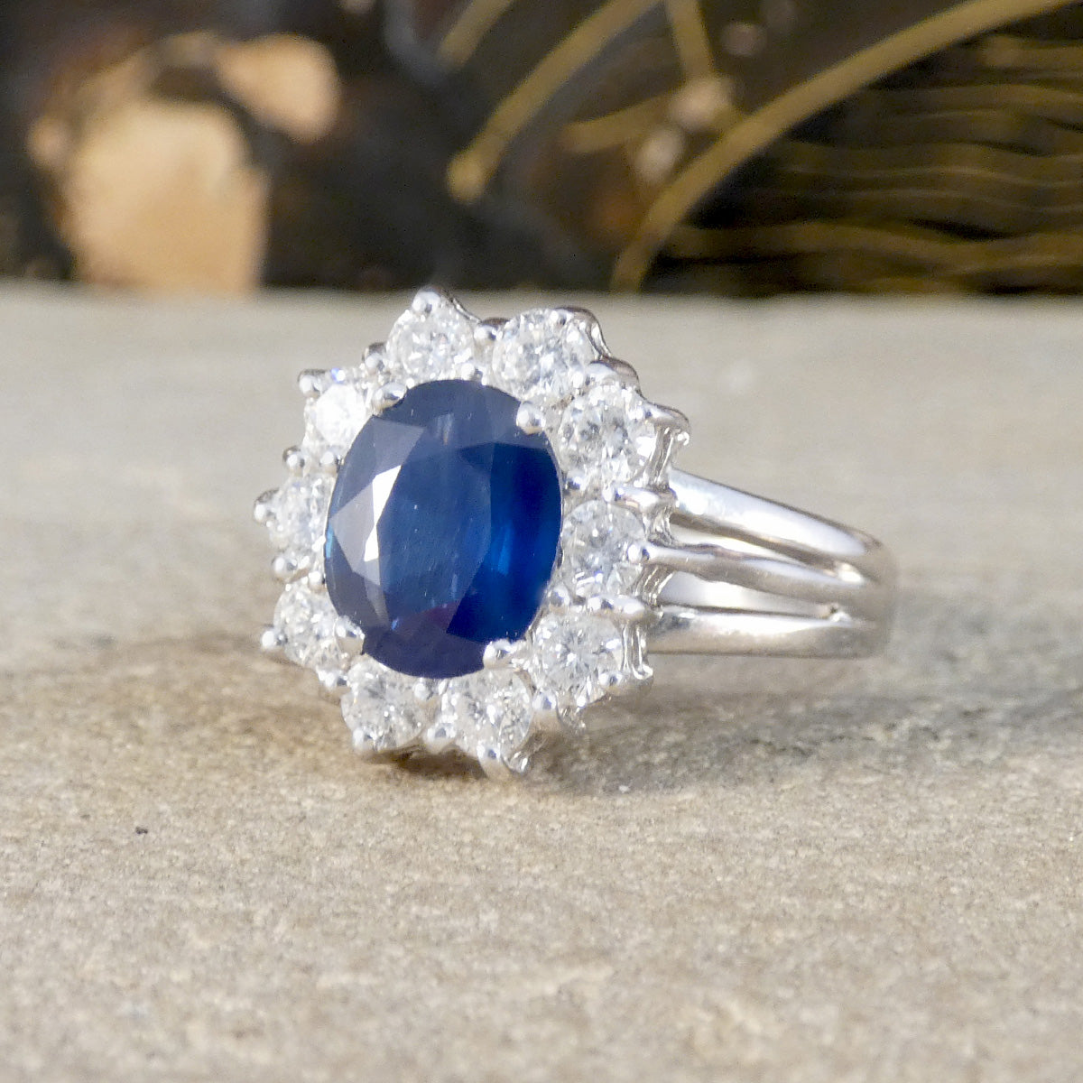 White Gold ring with a blue gemstone and diamond stones on a neutral background