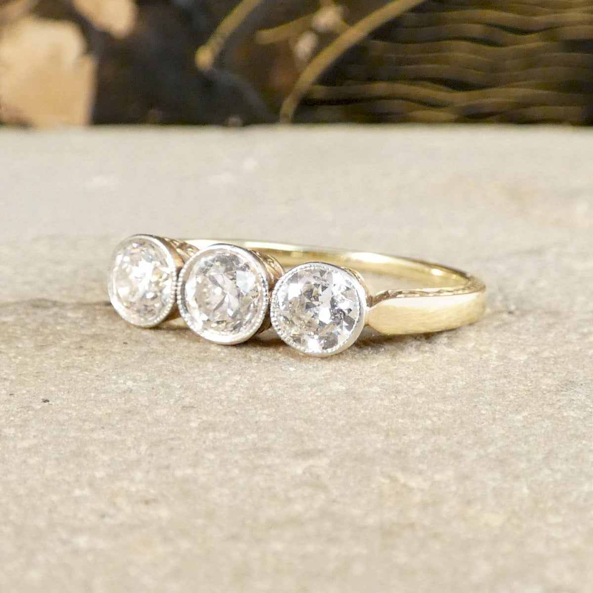Gold ring with three diamonds on a textured surface