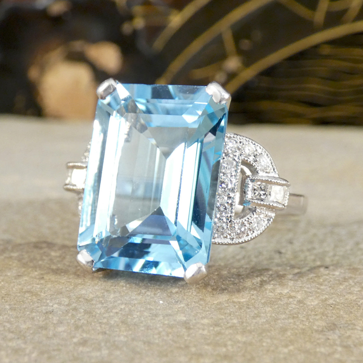 Ring with a large blue topaz gemstone and diamond-studded band on a neutral background