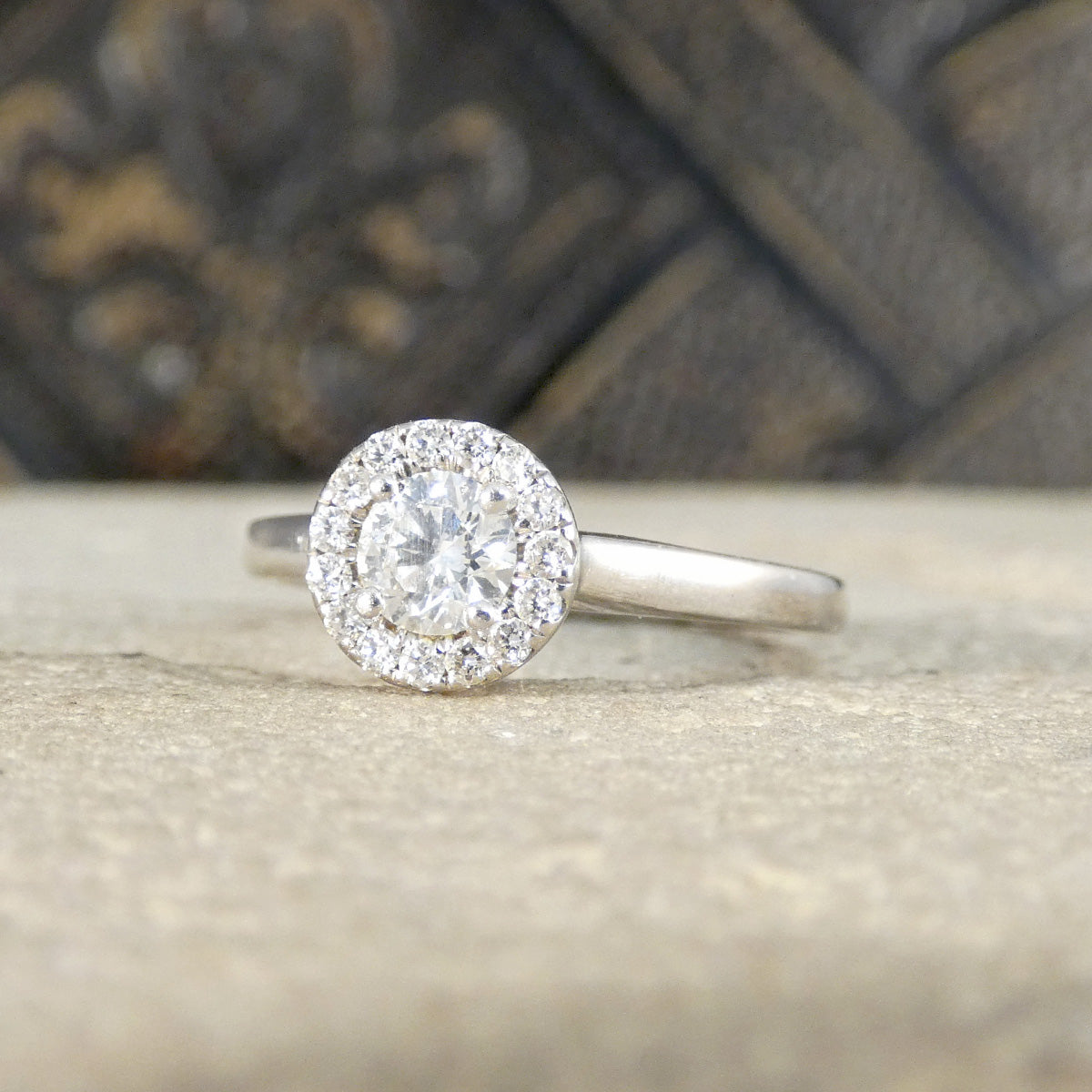 Diamond ring with a halo setting on a textured surface