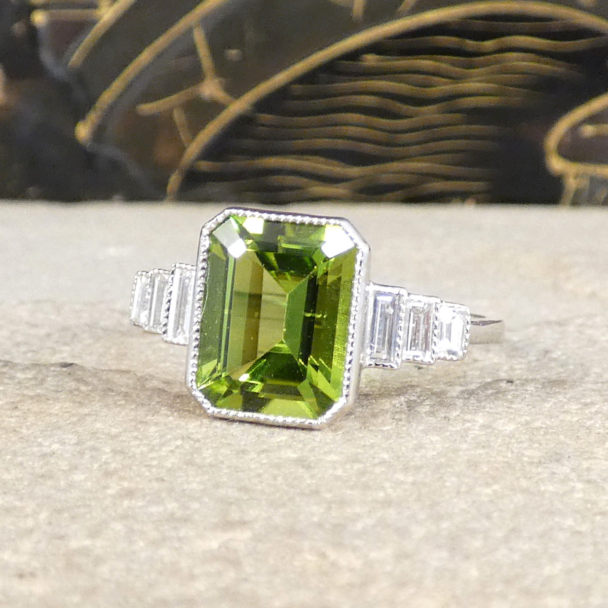 Art Deco Inspired Peridot and Baguette Cut Diamond Staged Shoulders in Platinum. showing a bright and beautifully vibrant green hue.