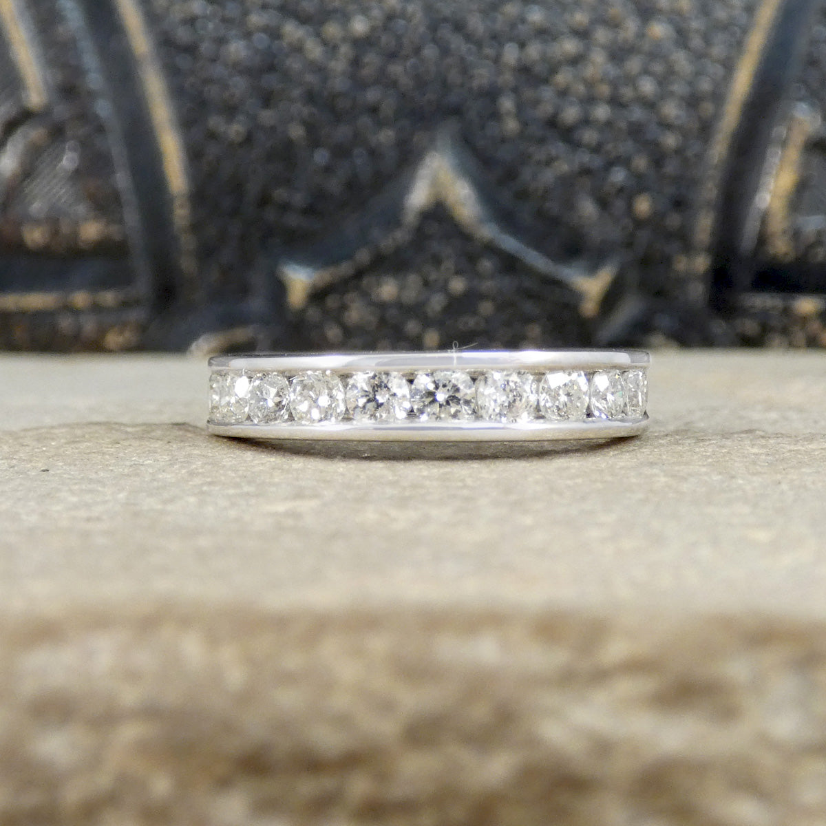 Diamond channel set ring on a textured surface with a blurred background