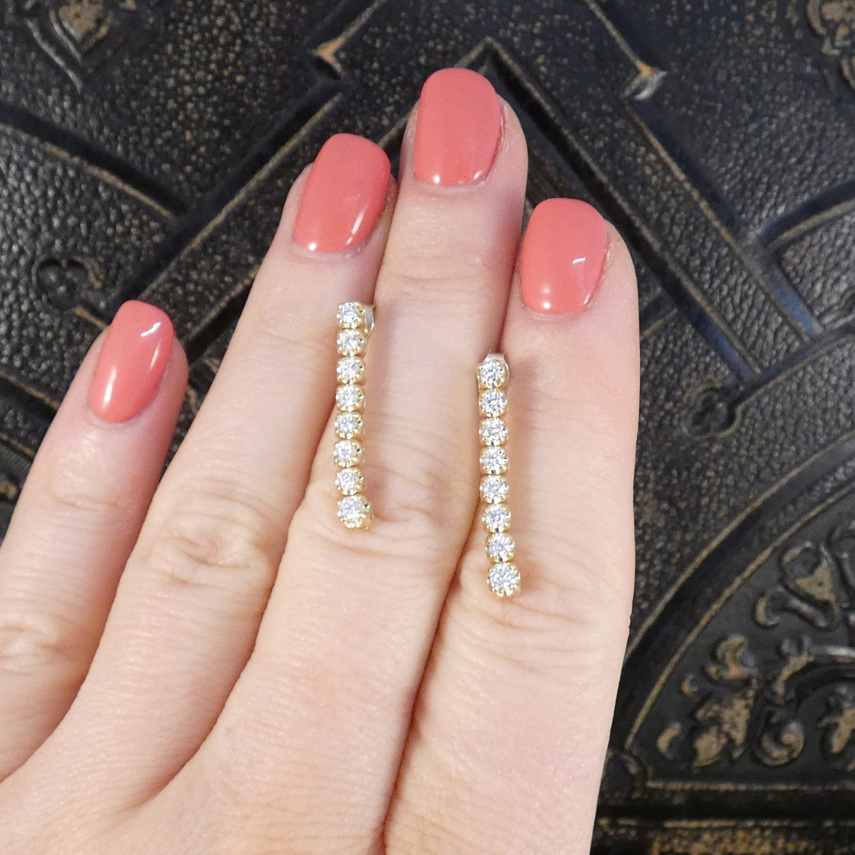 Diamond drop earring sin 9ct yellow gold displayed on a hand for size context.