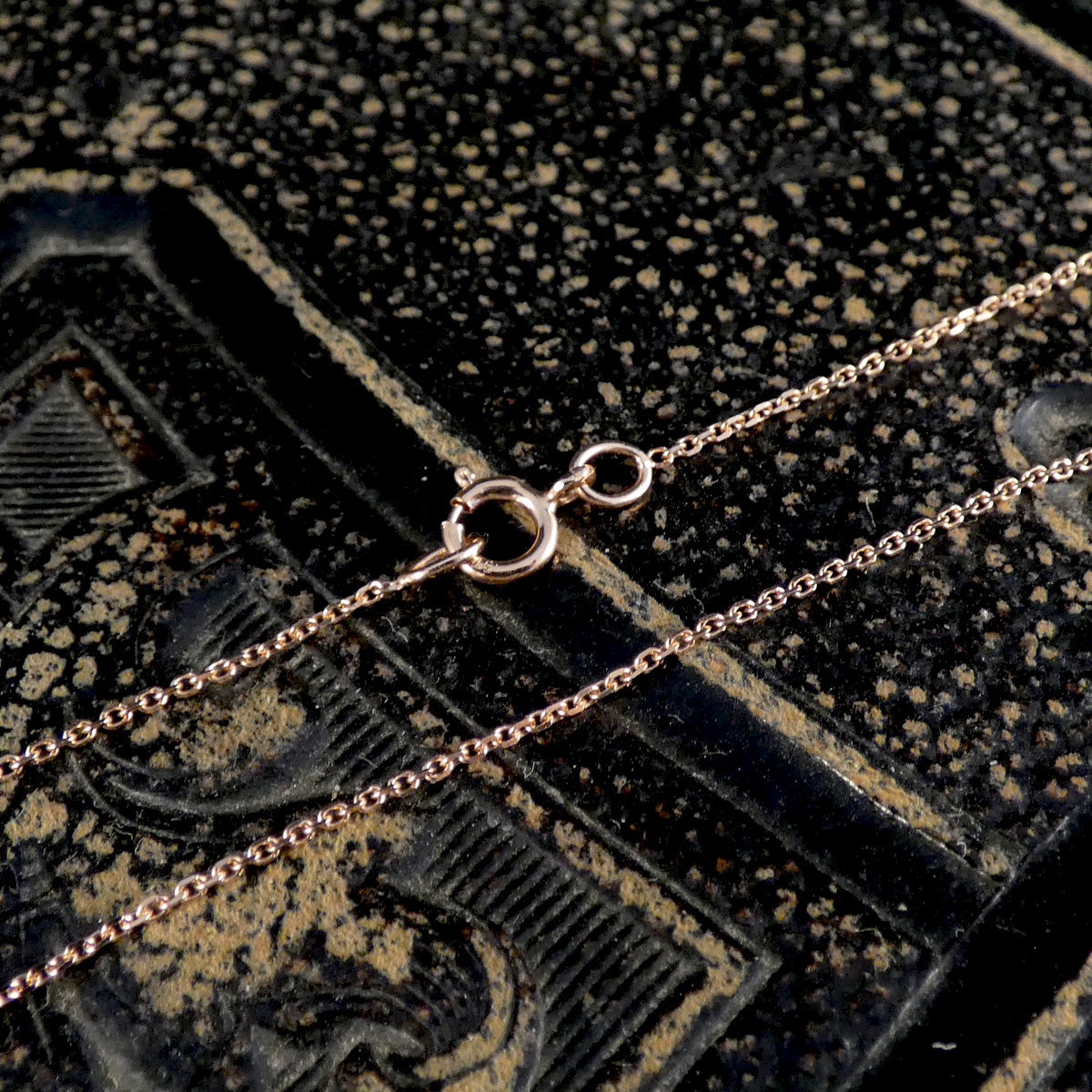 Rose gold chain on a textured black surface