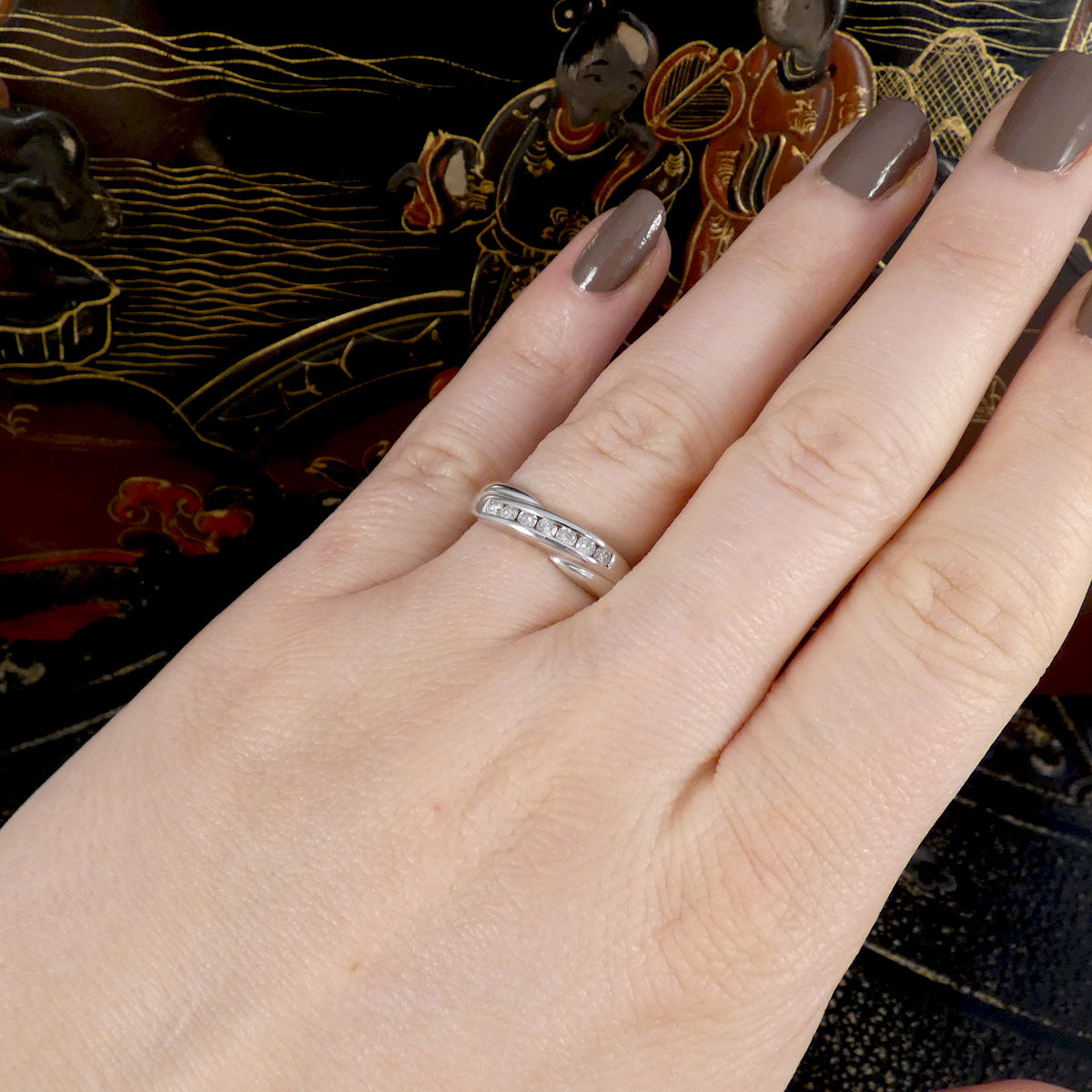 Hand wearing a white gold ring with a decorative background