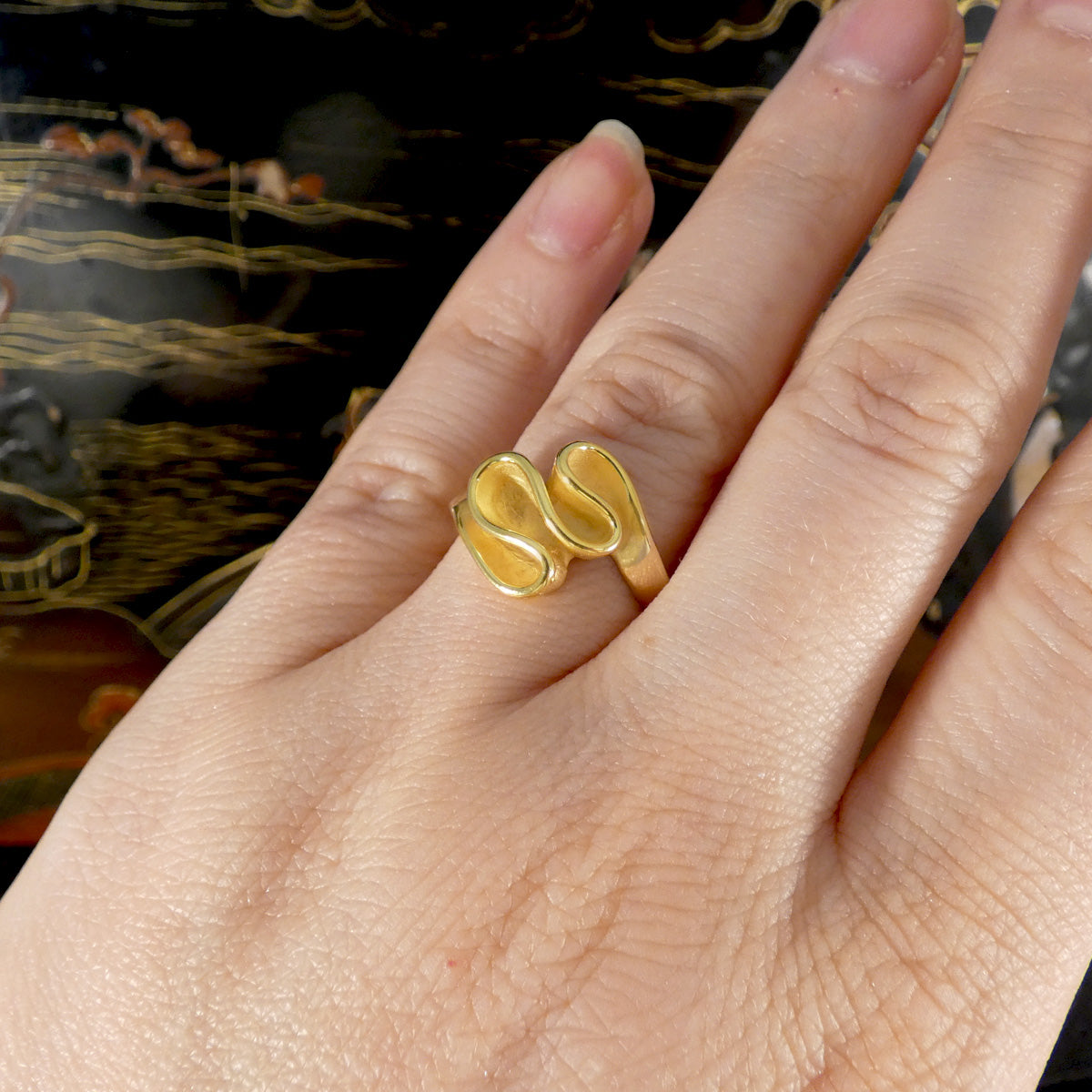 Gold ring on a person's finger with a decorative background