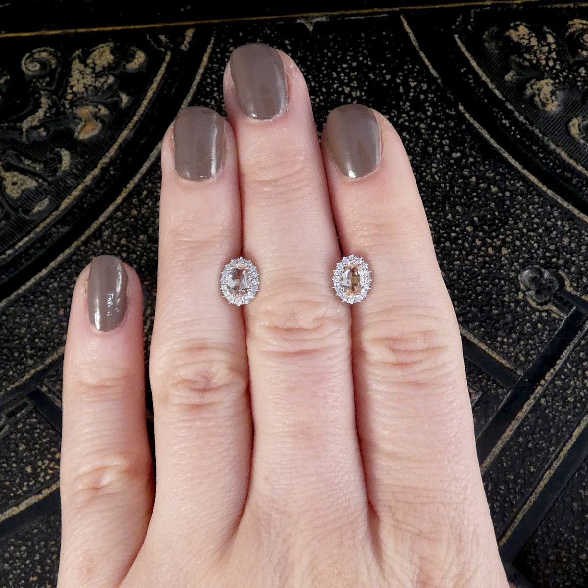 A pair of Morganite and Diamond Cluster Earrings in 18ct Rose Gold shown on the hand