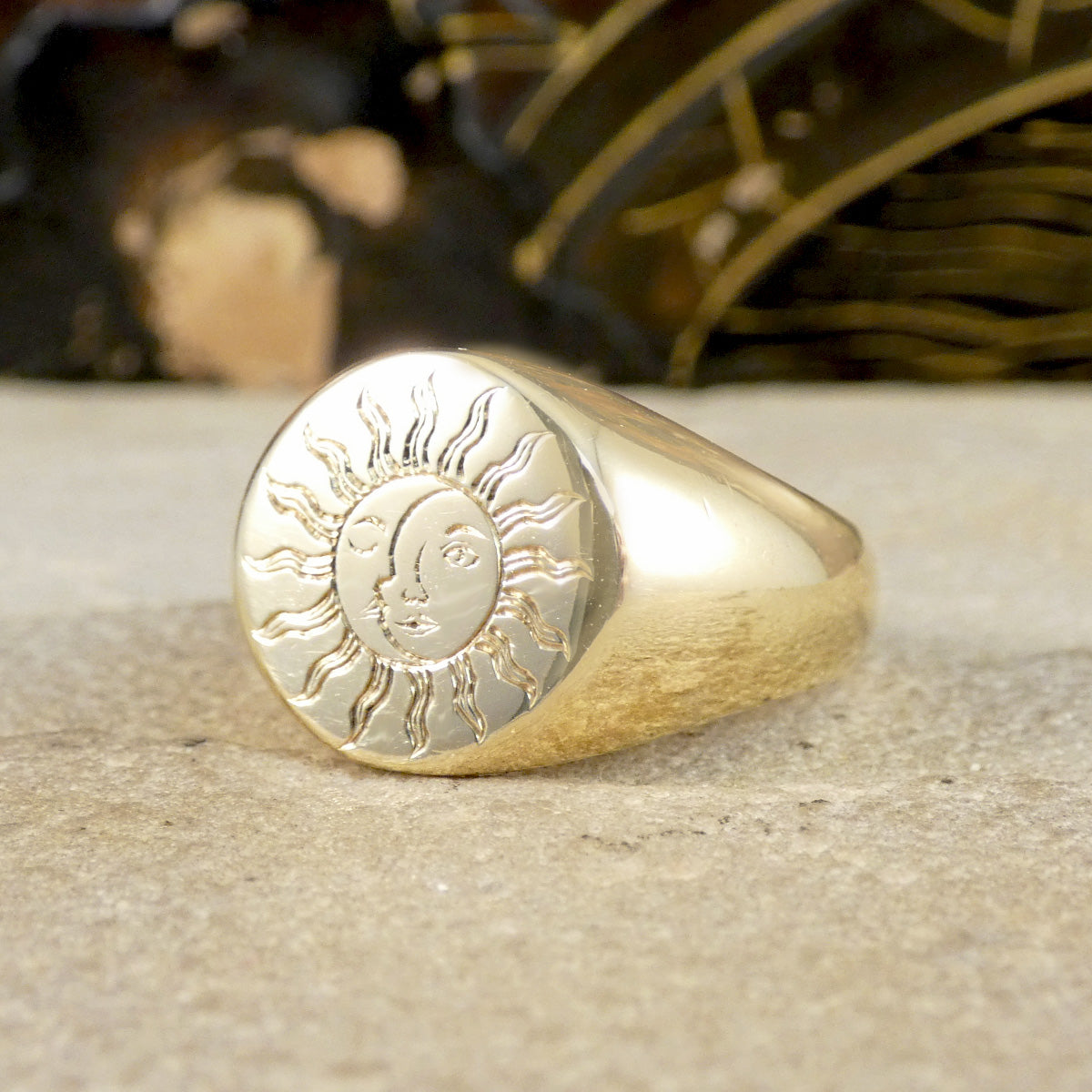 A solid yellow gold signet ring with a face engraved with a sun and moon