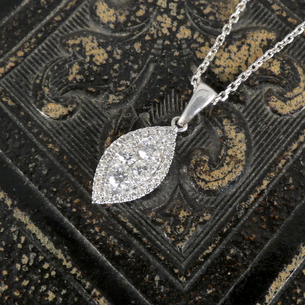 Silver leaf-shaped pendant necklace on a decorative black background