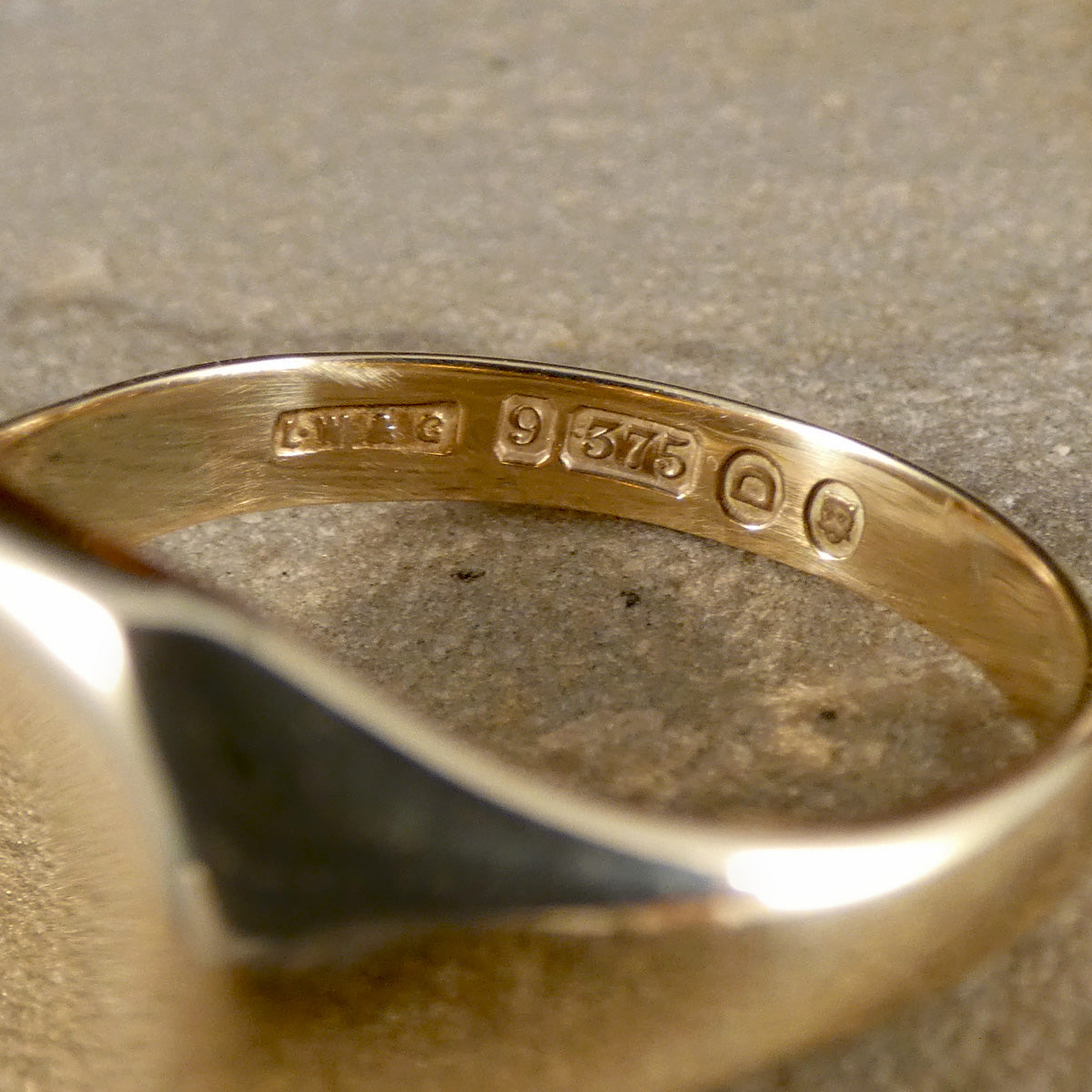 Gold ring with visible hallmarking on a textured surface