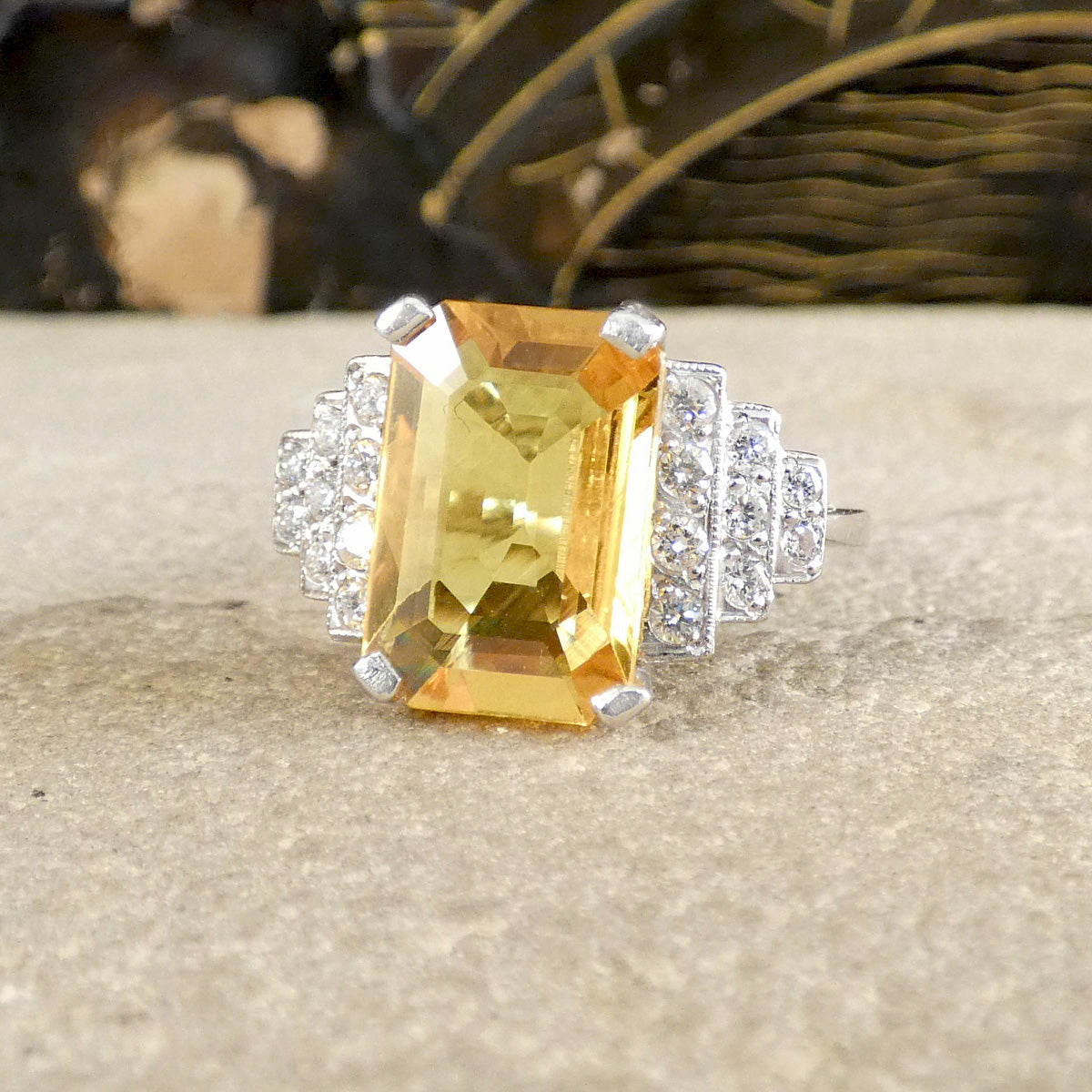 Ring with a large yellow gemstone and smaller diamonds on a textured surface