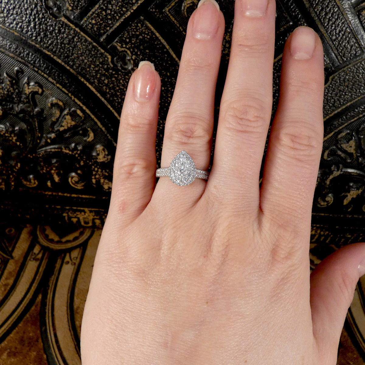 Hand wearing a diamond ring with a decorative background