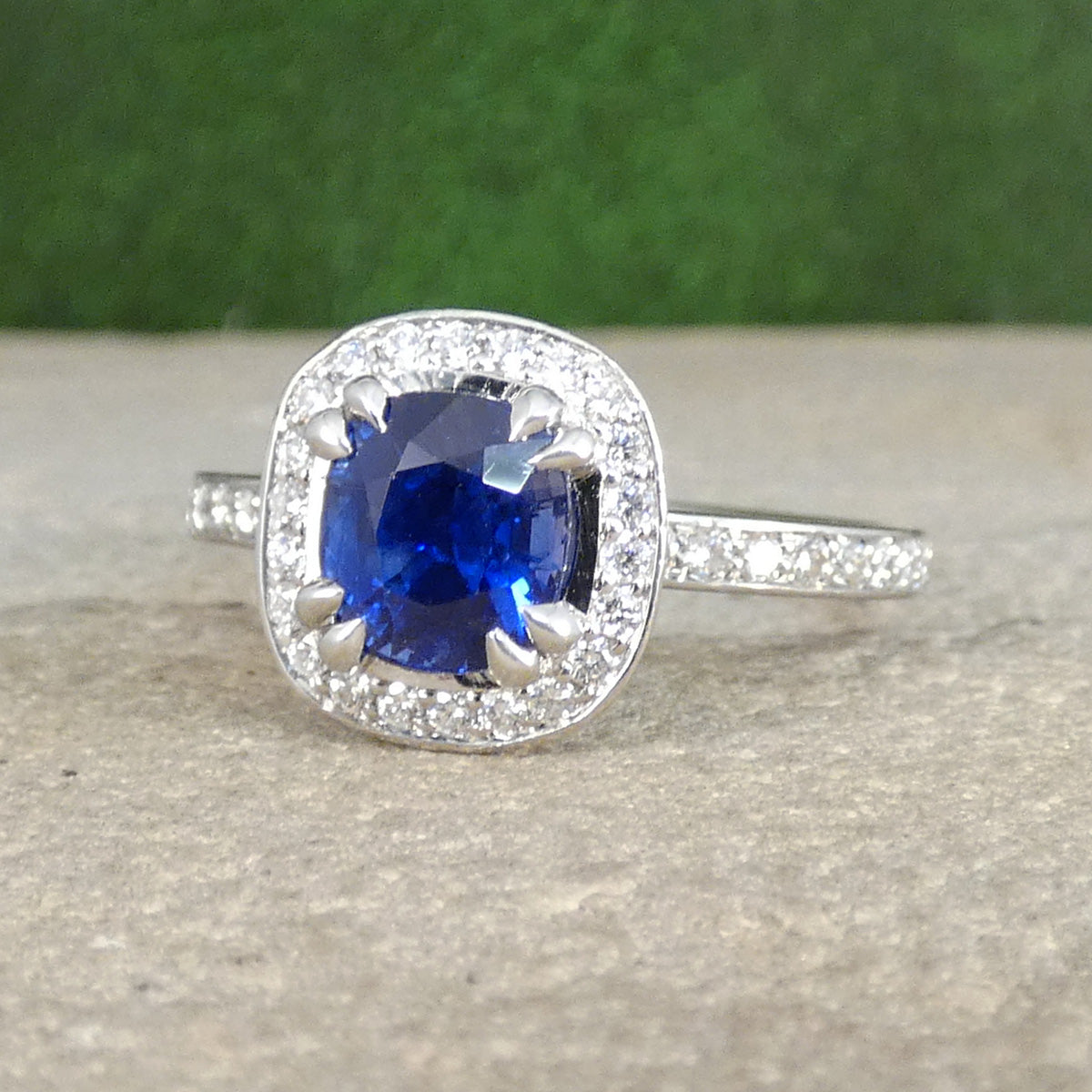 Silver ring with a blue gemstone on a textured surface with a green background