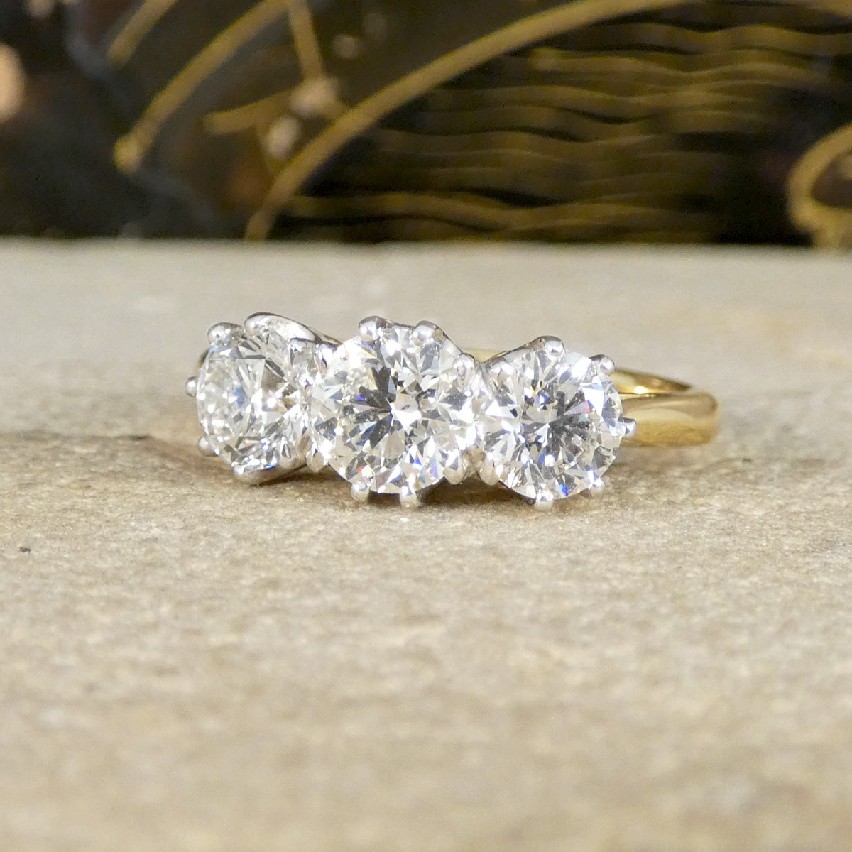 Gold ring with three diamonds on a textured surface