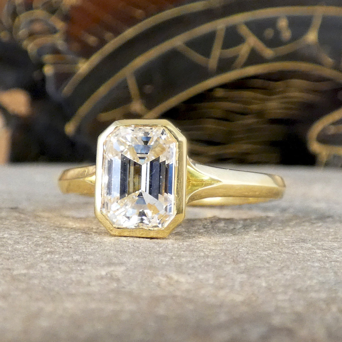 1.55ct Emerald Cut Diamond Solitaire in a Bezel Setting in 18ct Yellow Gold, showcasing a clear and bright diamond graded F/VS
