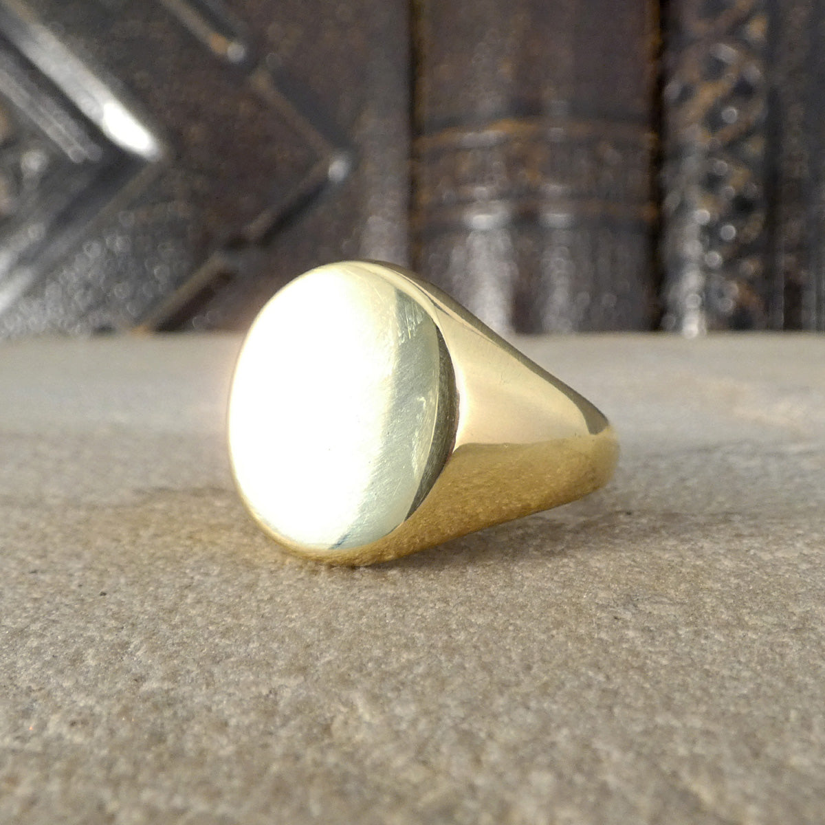 Solid Gold Signet Ring in 18ct Yellow Gold on a textured surface with a blurred background