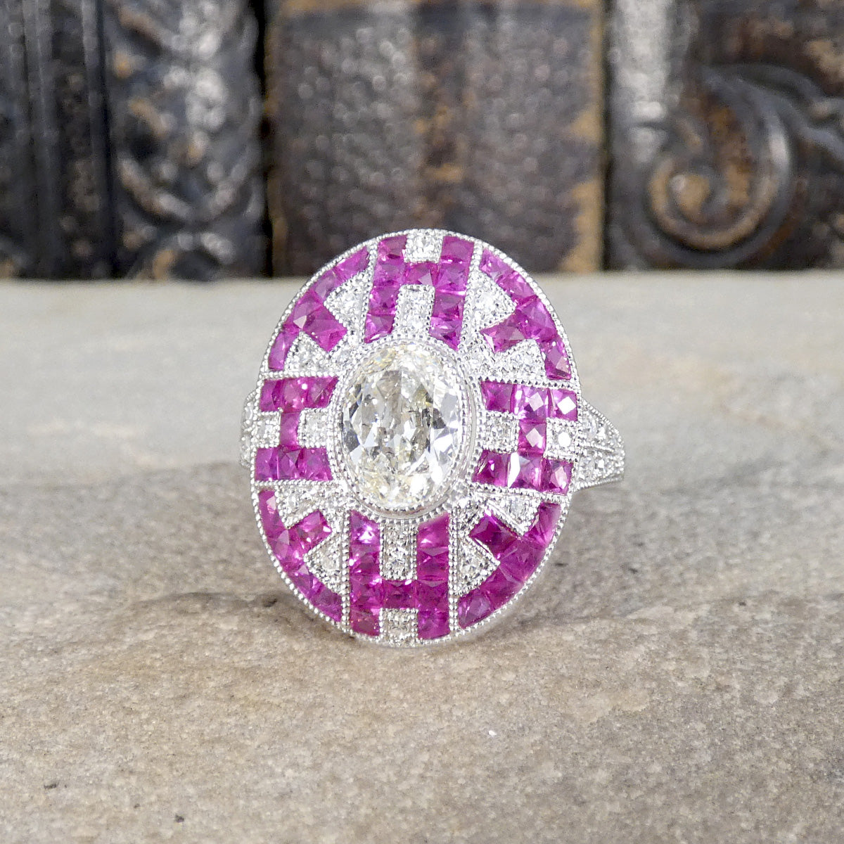 Displayed quality craftsmanship featuring an oval cut diamond centre with a surround of geometric patterned Rubies and Diamonds. 