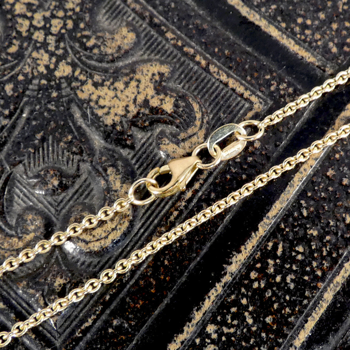 Gold chain necklace on an ornate black background