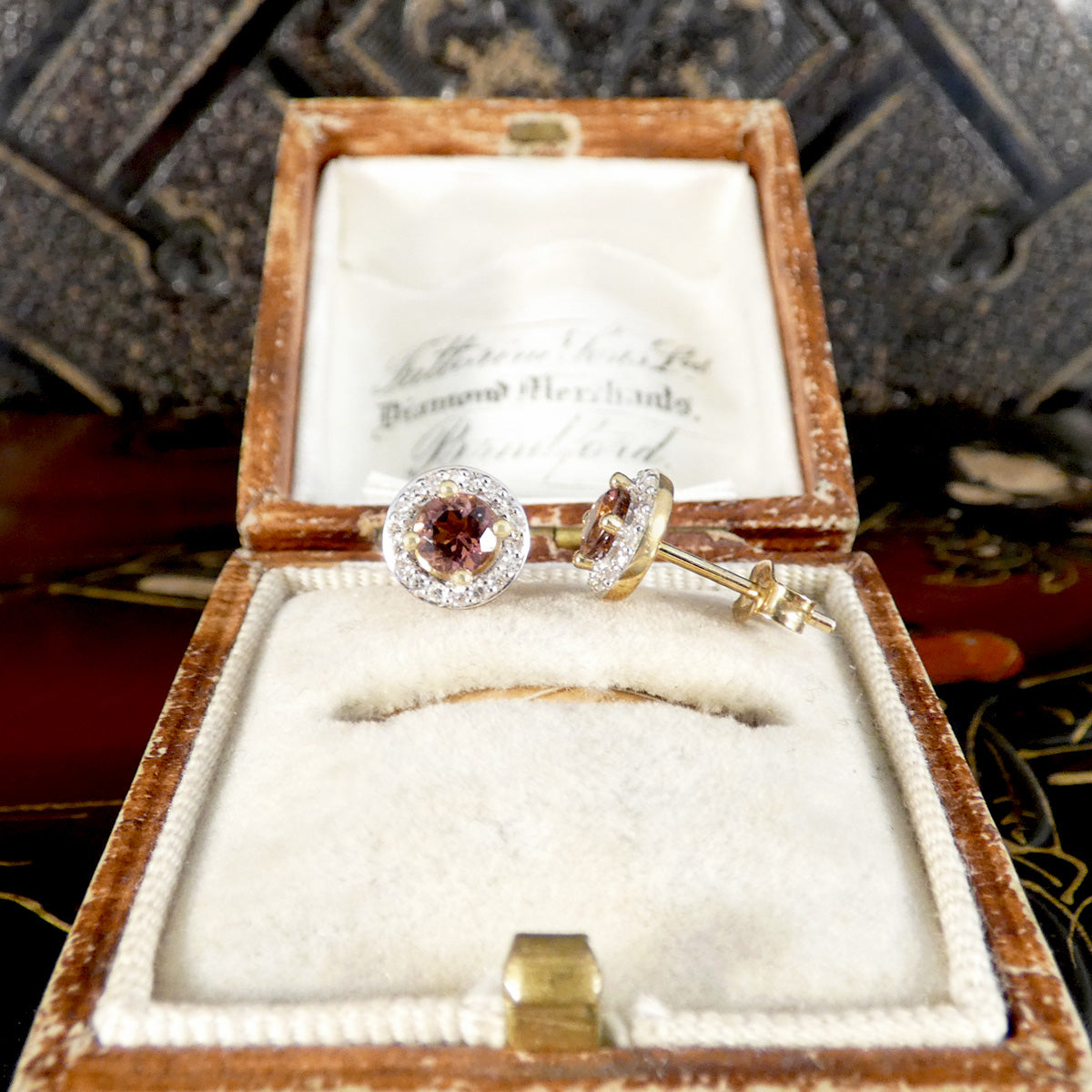 Gold ring with a diamond and brown gemstone in an open jewelry box.