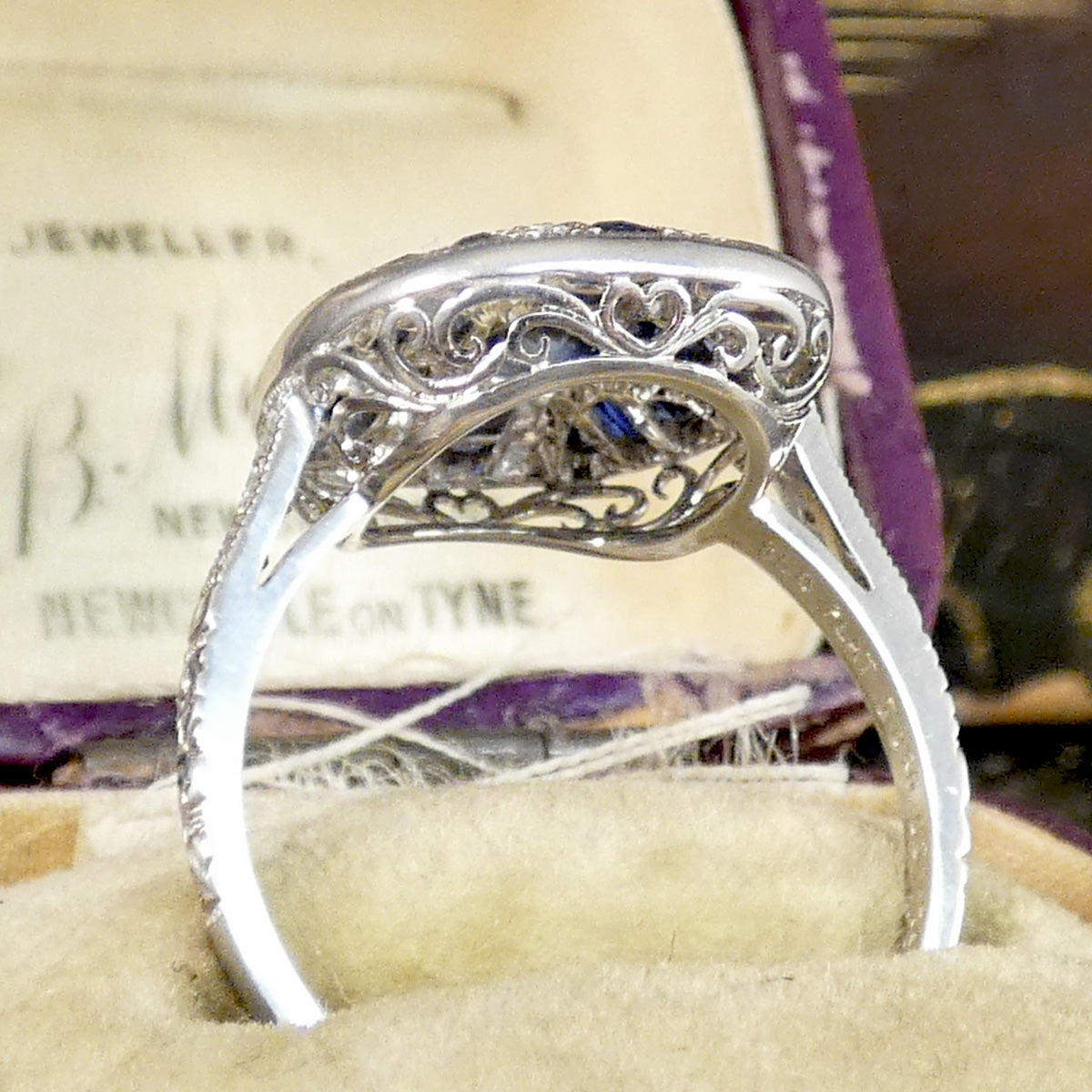 Side profile of sapphire and diamond cluster ring in platinum with a beautifully detailed gallery setting.