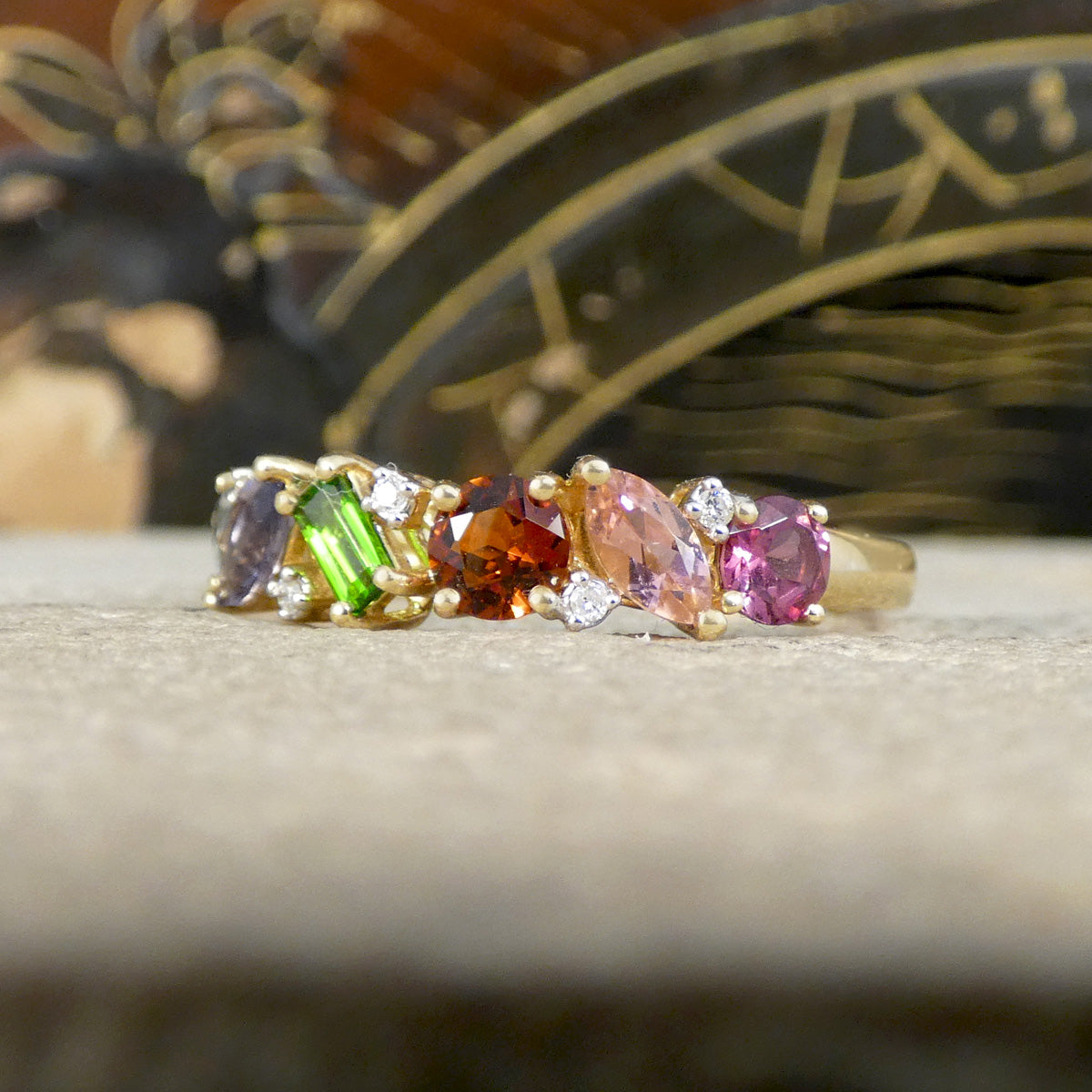 Gold ring with multicolored gemstones on a textured surface