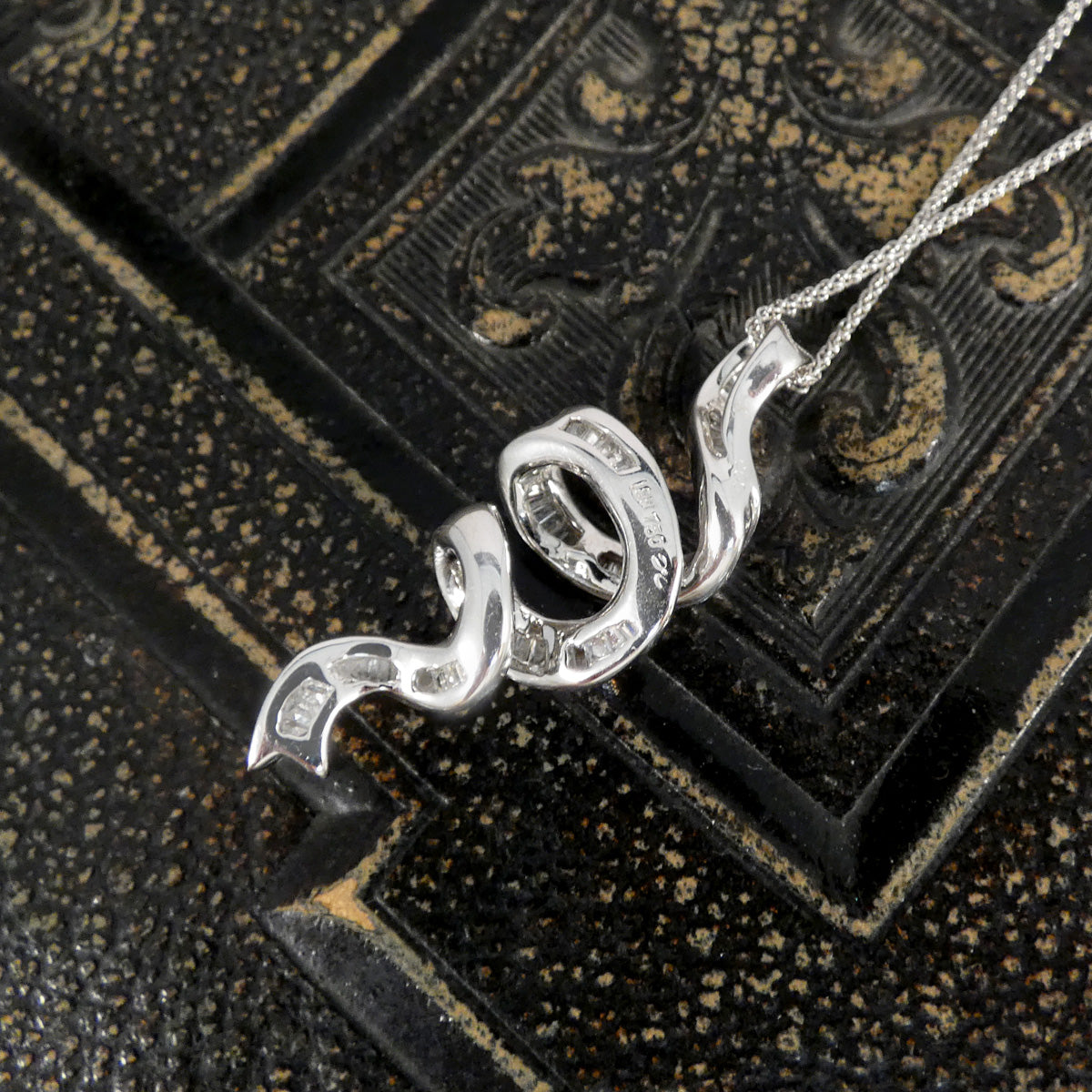 Ribbon shaped pendant shown from behind with marks 