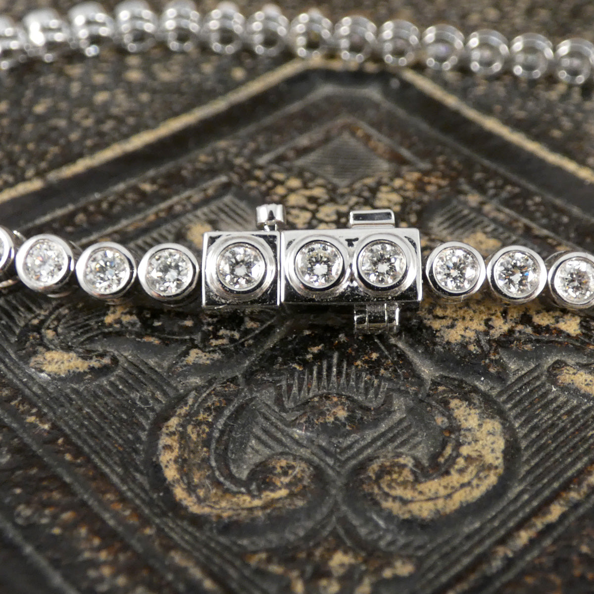 A diamond tennis bracelet in a bezel setting in Platinum showing secure clasp