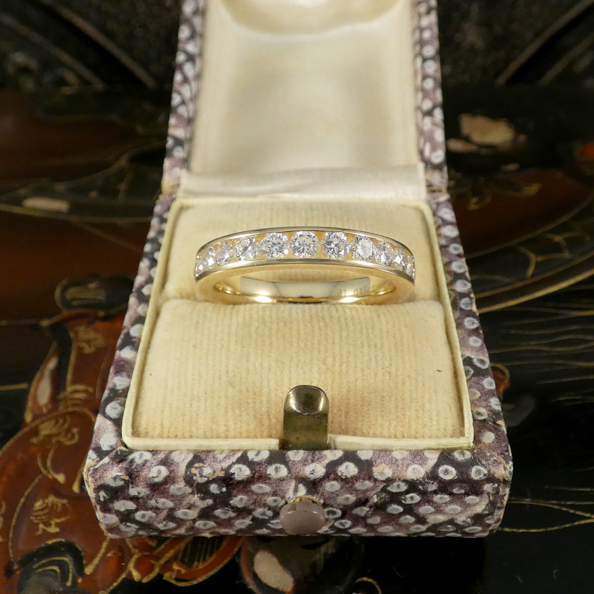 Gold ring with diamonds in a patterned jewelry box