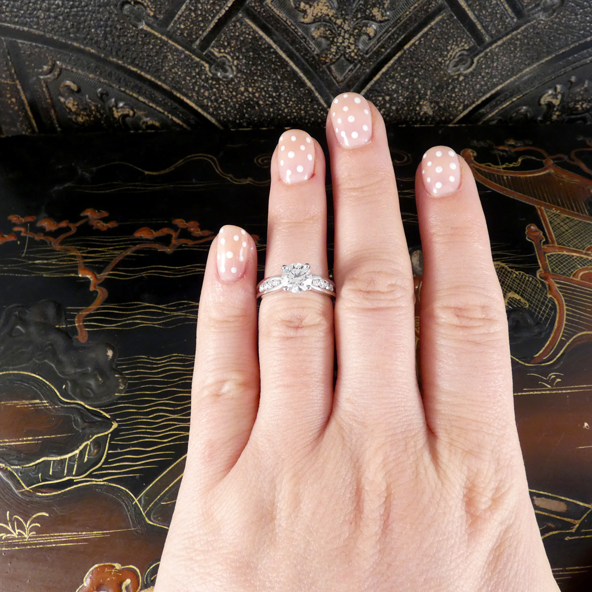Hand wearing a diamond ring with decorative background